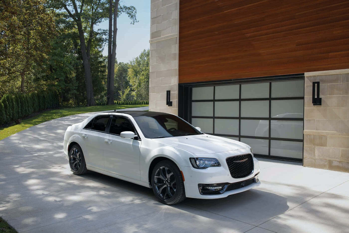 Chrysler 桌布 壁紙 — 一輛時尚的白色豪華轎車停放在陽光灑落的車道上，前方是一棟現代木石結構房屋。