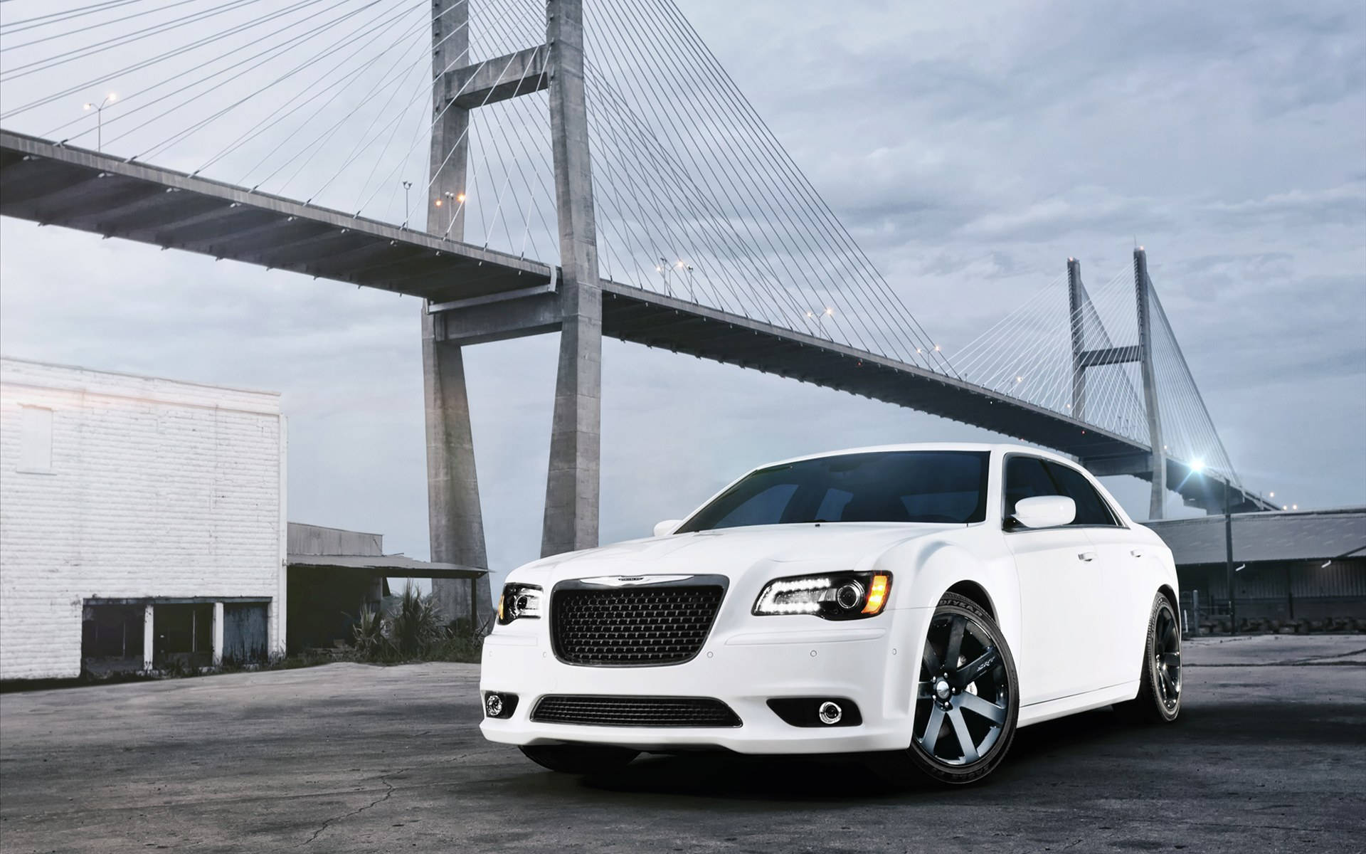 Chrysler 桌布 壁紙 — 一輛時尚的白色豪華轎車停泊在一個巨大的現代斜張橋下，天氣陰沉。
