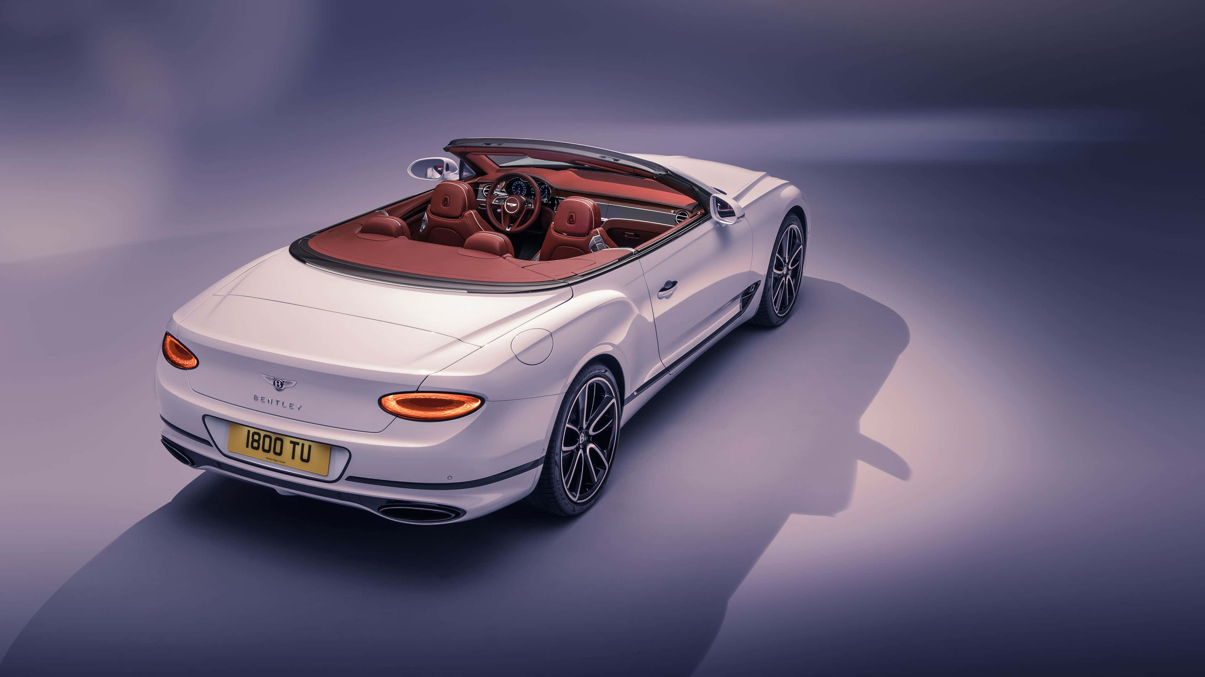 Bentley Continental Gt Convertible 桌布 壁紙 — 一輛時尚的白色賓利敞篷車，配以紅色皮革內飾，在紫色漸變背景的攝影棚燈光下閃耀。