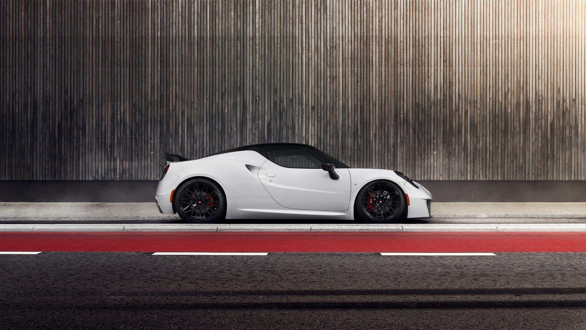 Alfa Romeo 4c 桌布 壁紙 — 一輛時尚的白色跑車，帶有黑色飾邊和紅色制動卡鉗，停在帶有紅色標記的道路上，旁邊是紋理木牆。