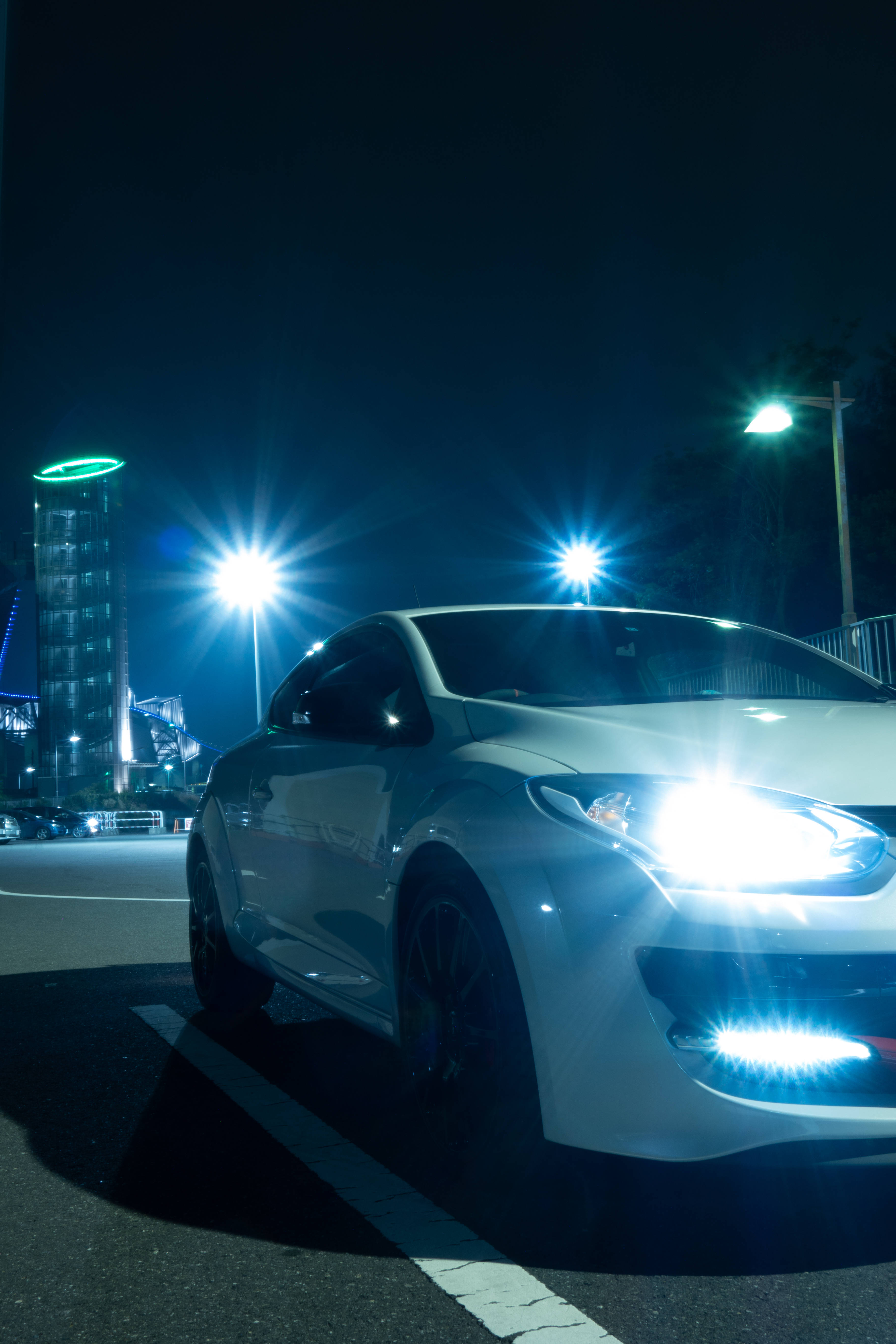 Renault 桌布 壁紙 — 一輛時尚的白色跑車在夜晚黑暗的城市街道上，在明亮的街燈下閃閃發光。