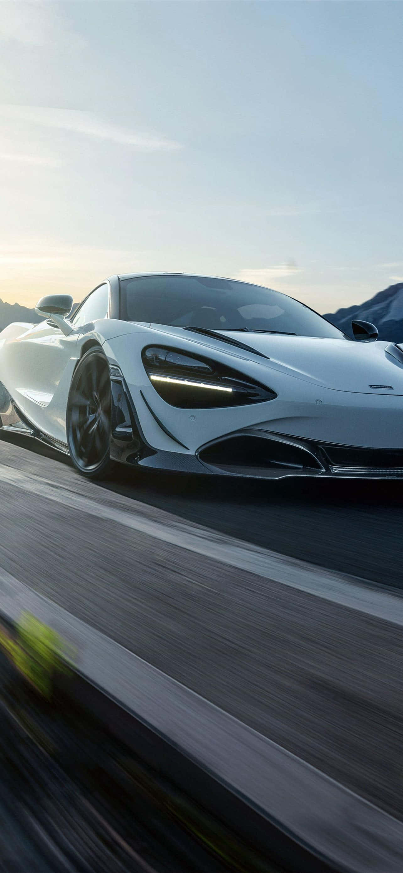 Cool Mclaren 桌布 壁紙 — 一輛時尚的白色跑車在日落時分沿著山路疾馳，帶有模糊的動態和戲劇性的燈光。
