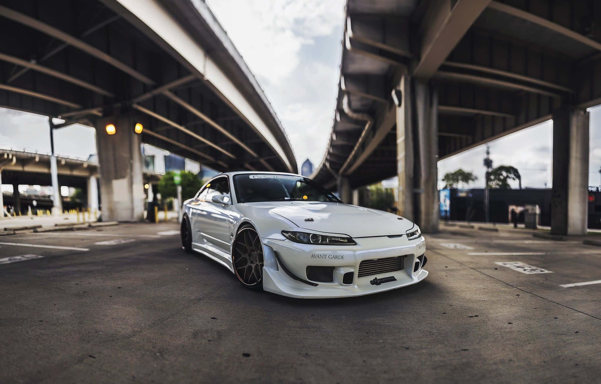 Nissan Silvia S15 桌布 壁紙 — 一輛時尚的白色跑車配備客製化輪圈，停在混凝土高架橋下，光線效果戲劇性。