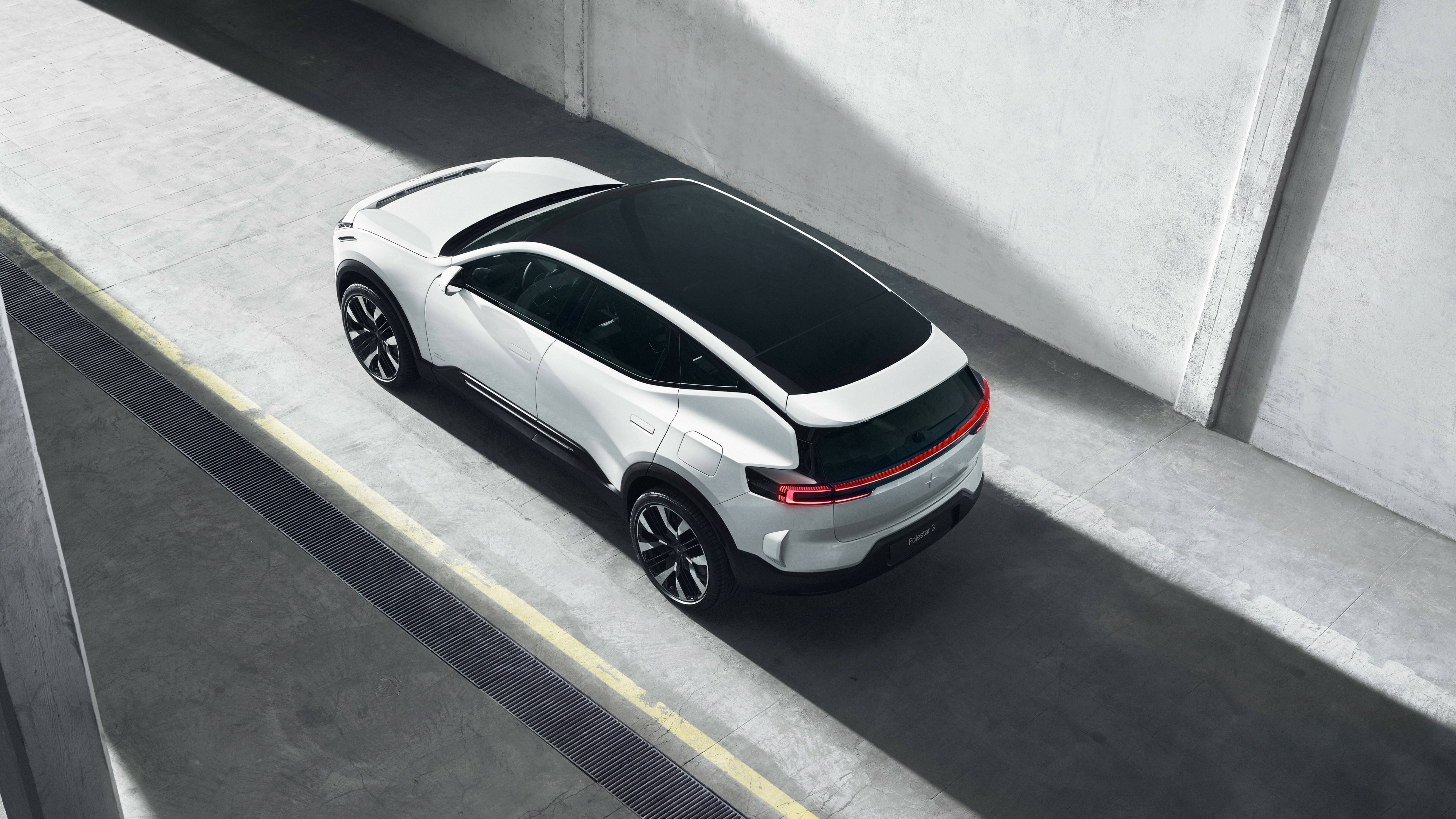 豪華車 桌布 壁紙 — 一輛時尚的白色電動SUV，配備黑色車頂和紅色尾燈，停在明亮的日光下的混凝土坡道上。