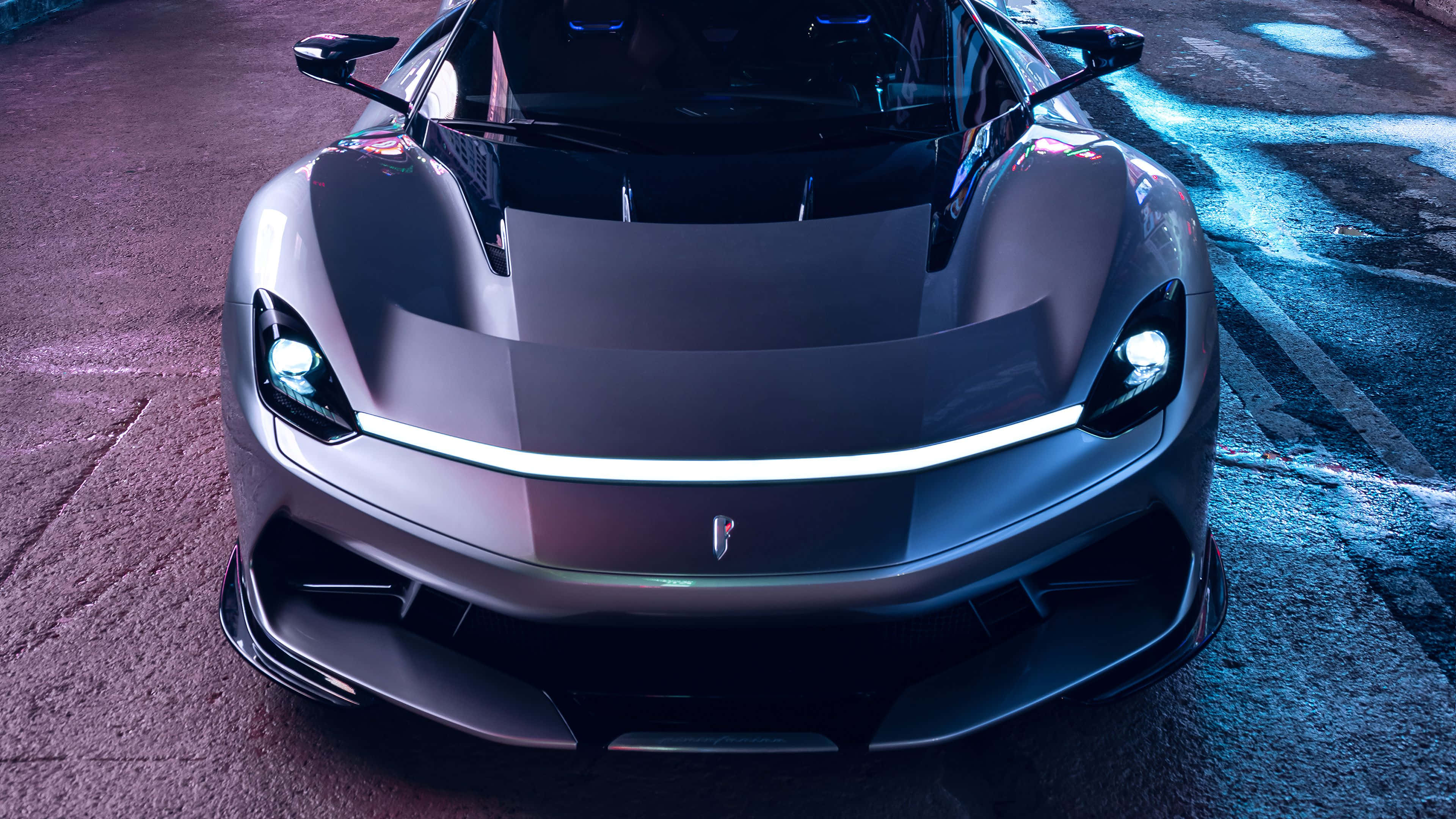 Pininfarina 桌布 壁紙 — 一輛時尚的磨砂灰色超跑，配備發光的頭燈和發光的前條紋，停在夜間潮濕的城市街道上。