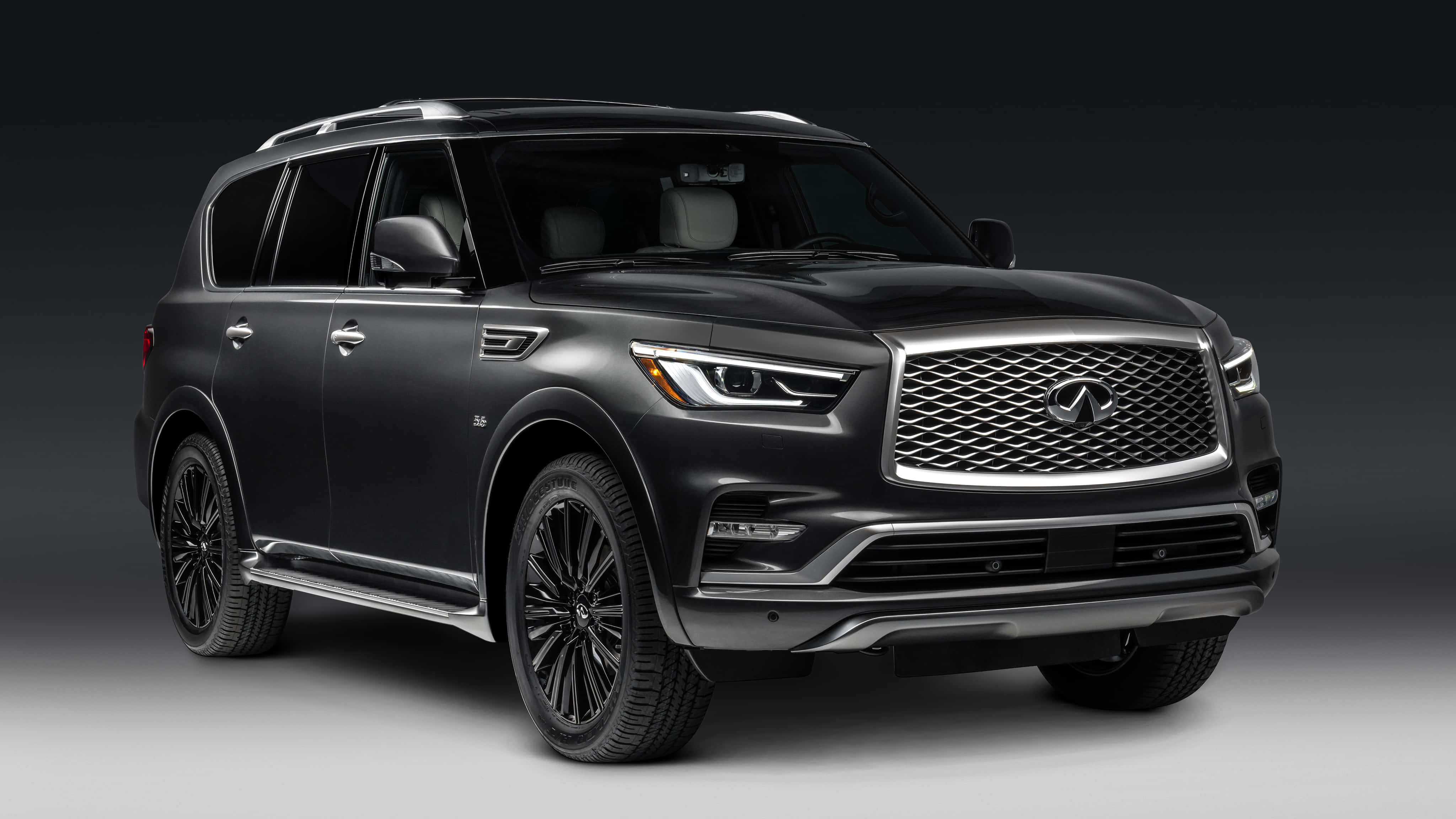 Infiniti Qx80 桌布 壁紙 — 一輛時尚的磨砂黑色Infiniti QX80 SUV，帶有鍍鉻裝飾和黑色輪圈，在深色漸變工作室背景前擺拍。