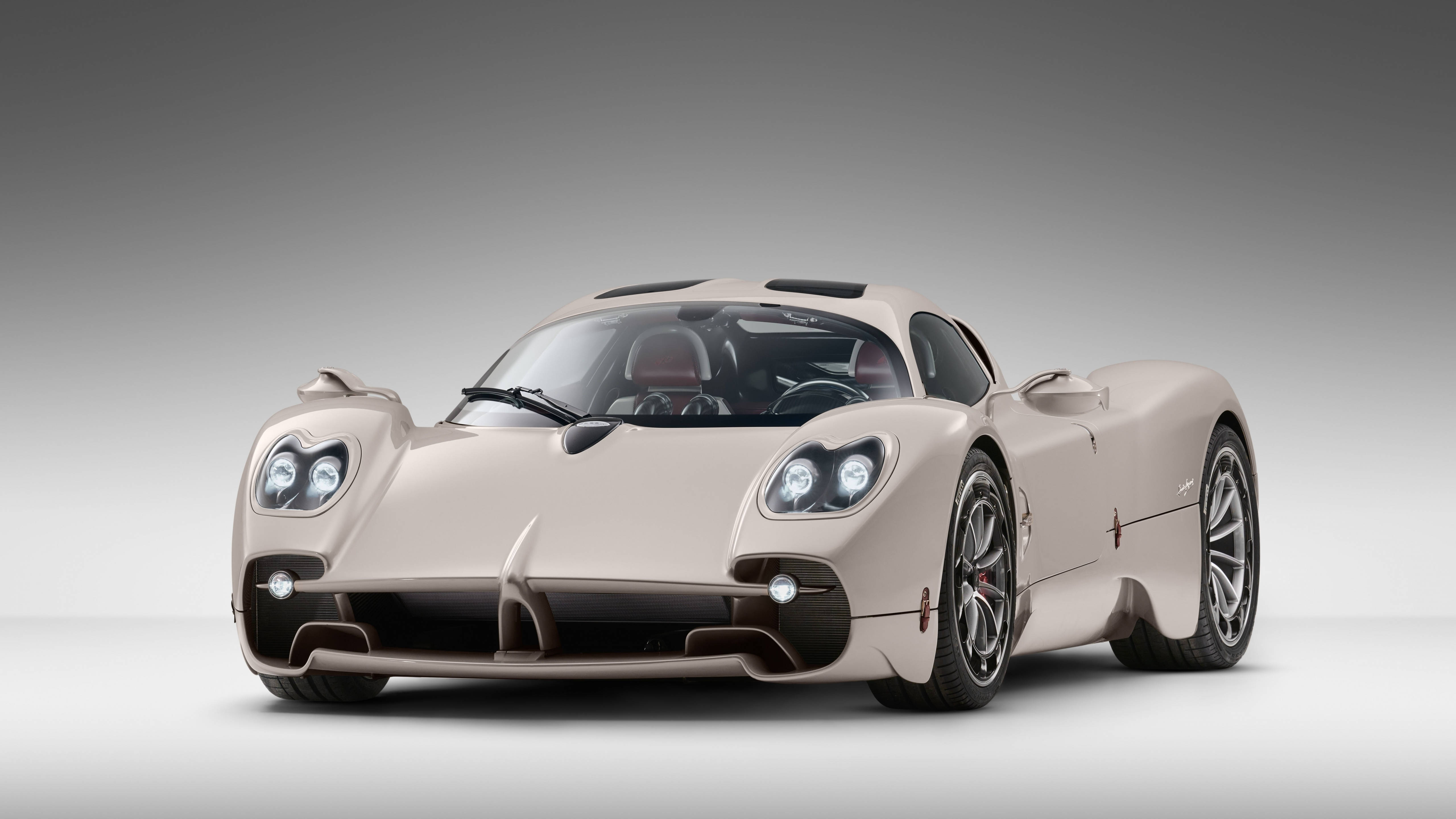 賽車 桌布 壁紙 — 一輛時尚的米色Pagani Zonda跑車，帶有發光的車頭燈和黑色飾邊，在漸變灰色工作室背景前擺姿勢。