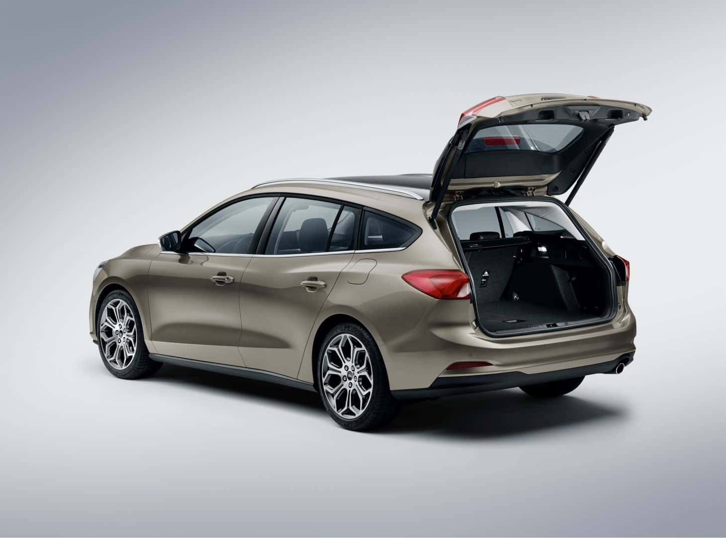 Ford Focus 桌布 壁紙 — 一輛時尚的米色旅行車，後尾門打開，在簡約的工作室背景下展示寬敞的貨物空間。