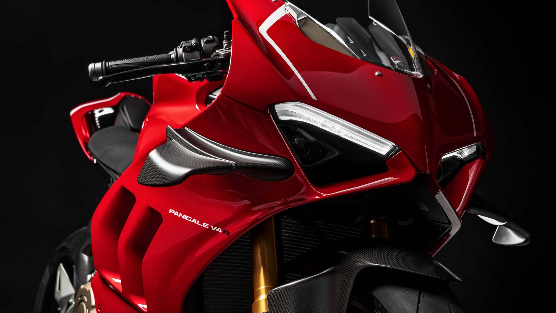 杜卡迪 桌布 壁紙 — 一輛時尚的紅色 Ducati Panigale V4R 摩托車在攝影棚燈光下，黑色背景襯托下閃閃發光。