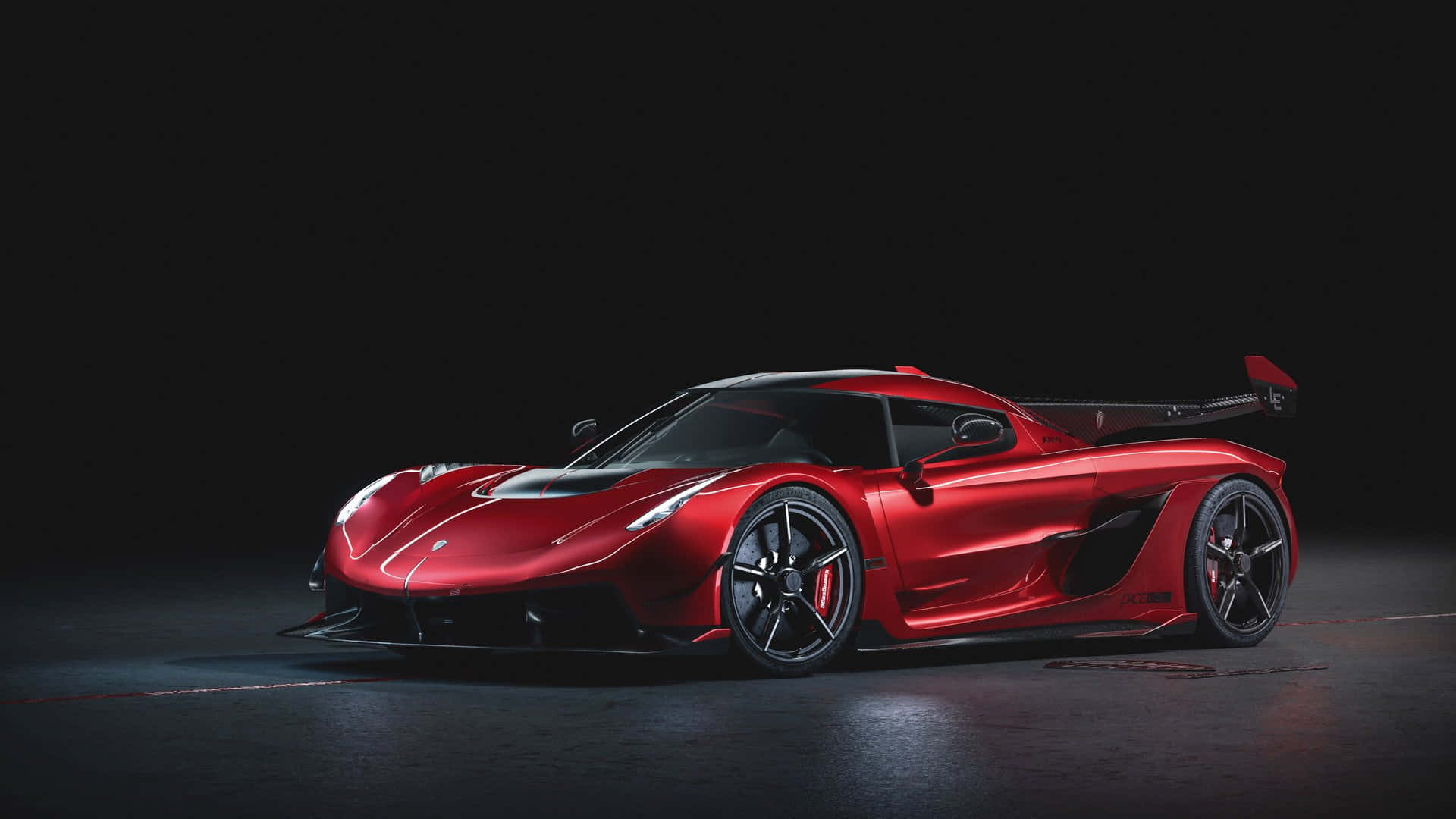 Koenigsegg 桌布 壁紙 — 一輛時尚的紅色 Koenigsegg 超跑在攝影棚燈光下，在純黑背景上閃閃發光。