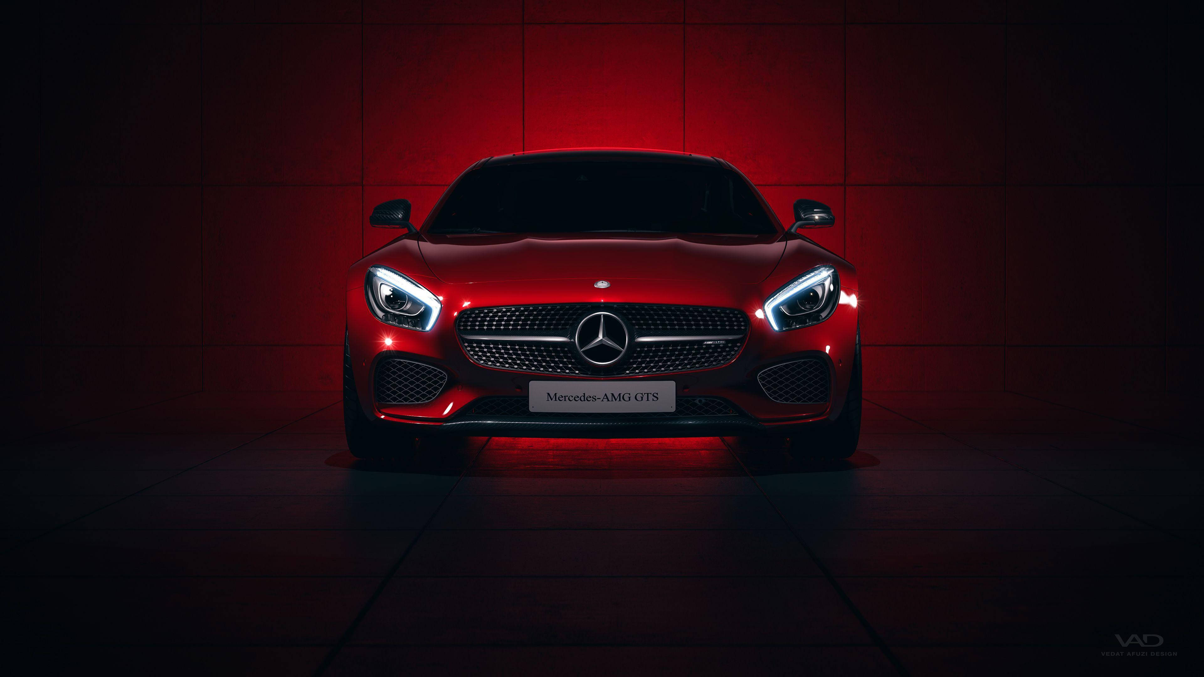 benz 4K 桌布 壁紙 — 一輛時尚的紅色 Mercedes-AMG GTS 跑車在戲劇性的紅色燈光下，在深色瓷磚牆前閃耀。