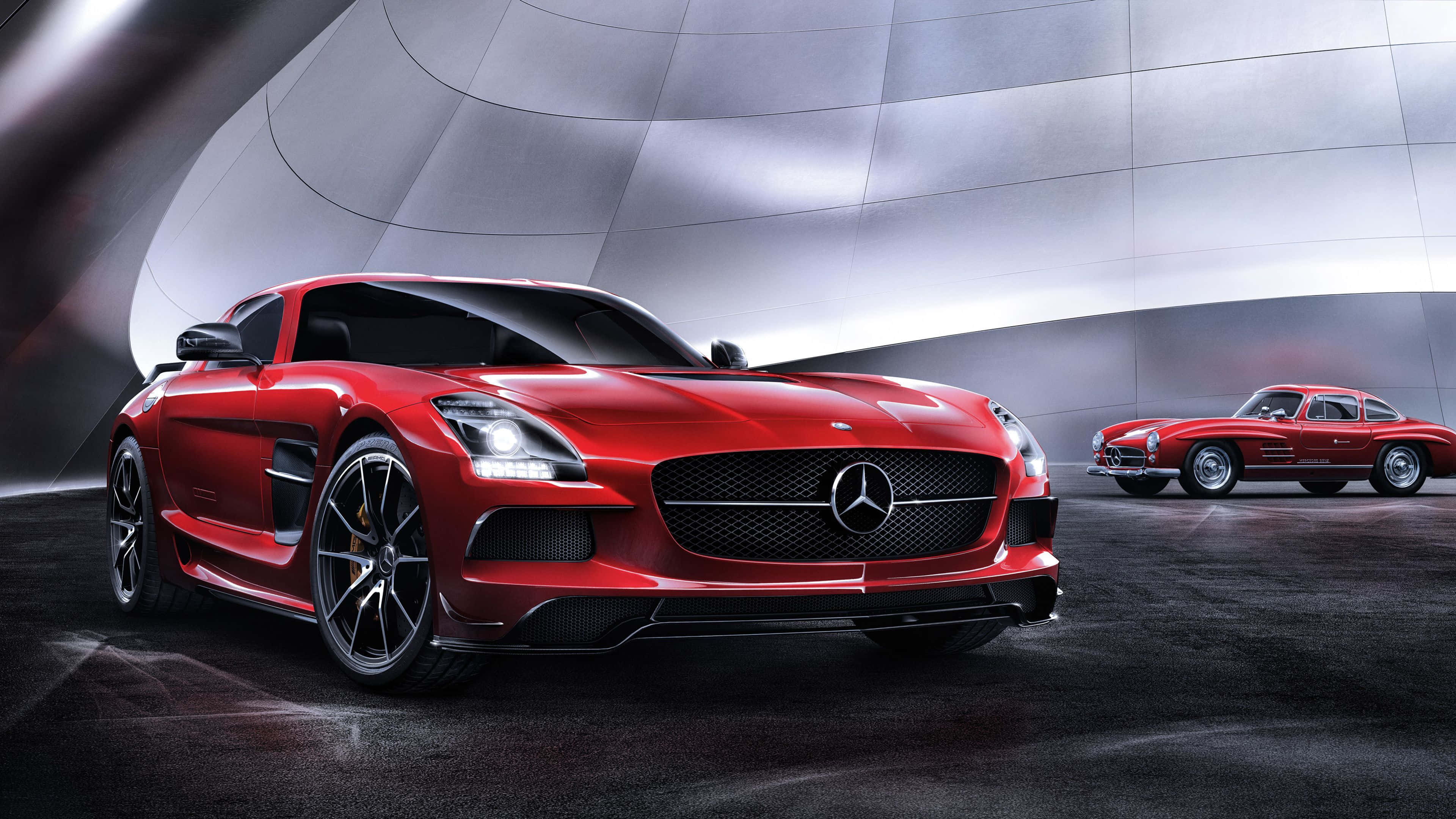 4K 奔馳壁紙 桌布 壁紙 — 一輛時尚的紅色 Mercedes SLS AMG 跑車在攝影棚燈光下閃閃發光，旁邊是一輛經典的紅色 Mercedes 300SL Gullwing。