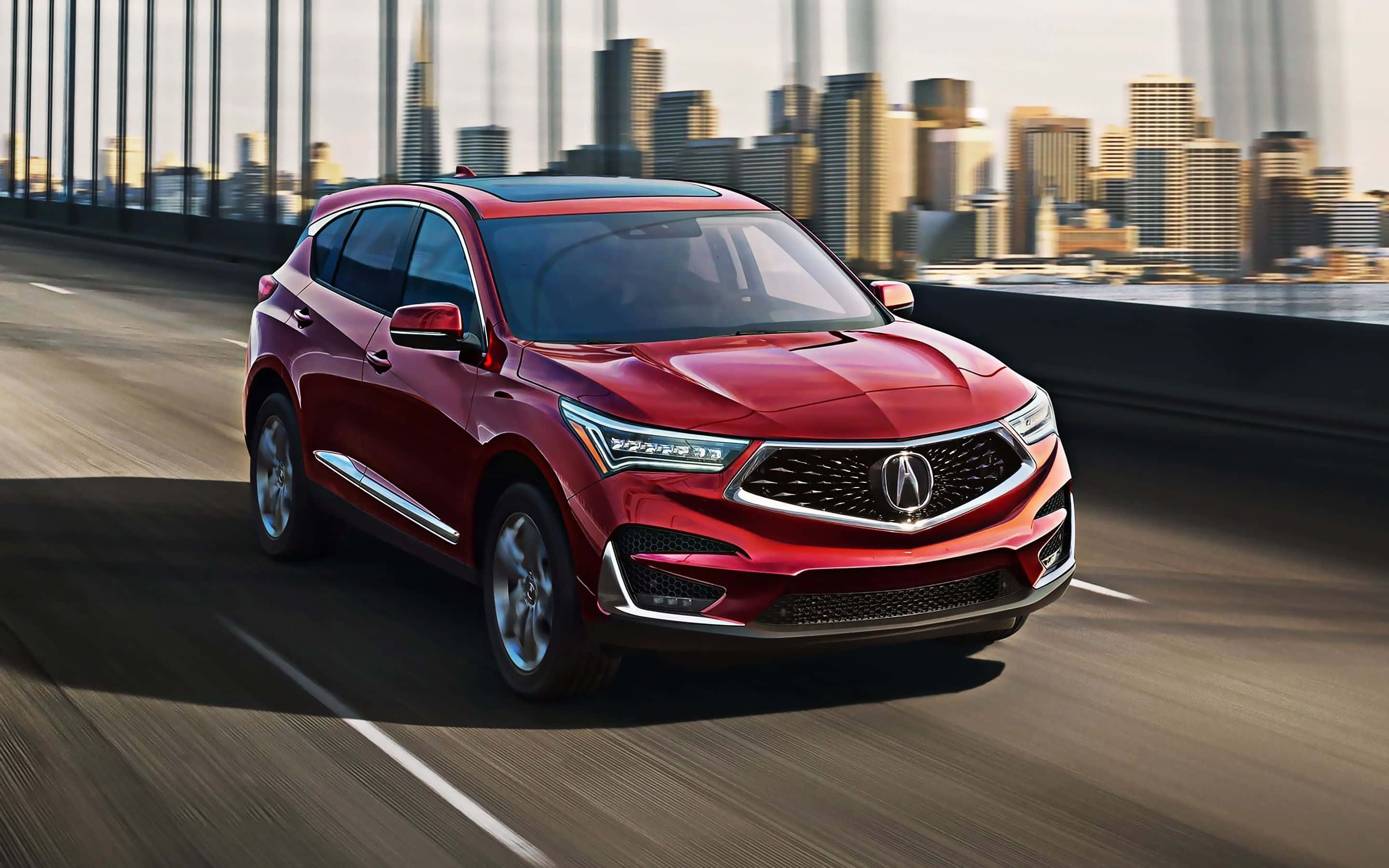 Acura Rdx 桌布 壁紙 — 一輛時尚的紅色Acura SUV在城市的橋樑上疾馳，背景是模糊的城市天際線。