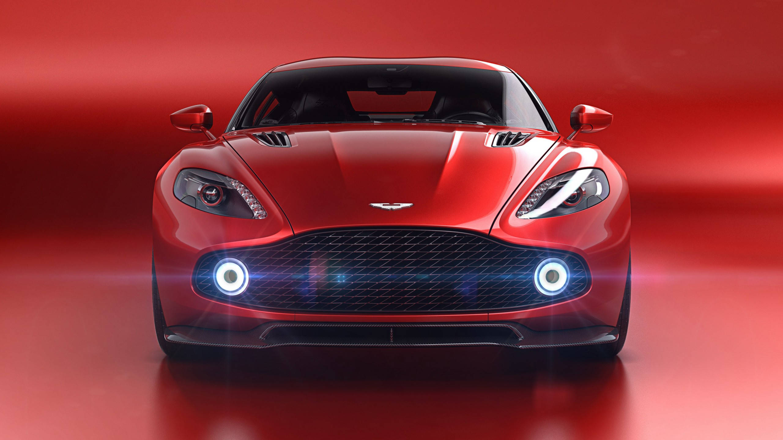 跑車 桌布 壁紙 — 一輛時尚的紅色Aston Martin跑車正面朝前，配備發光的車頭燈，背景是充滿活力的紅色攝影棚。