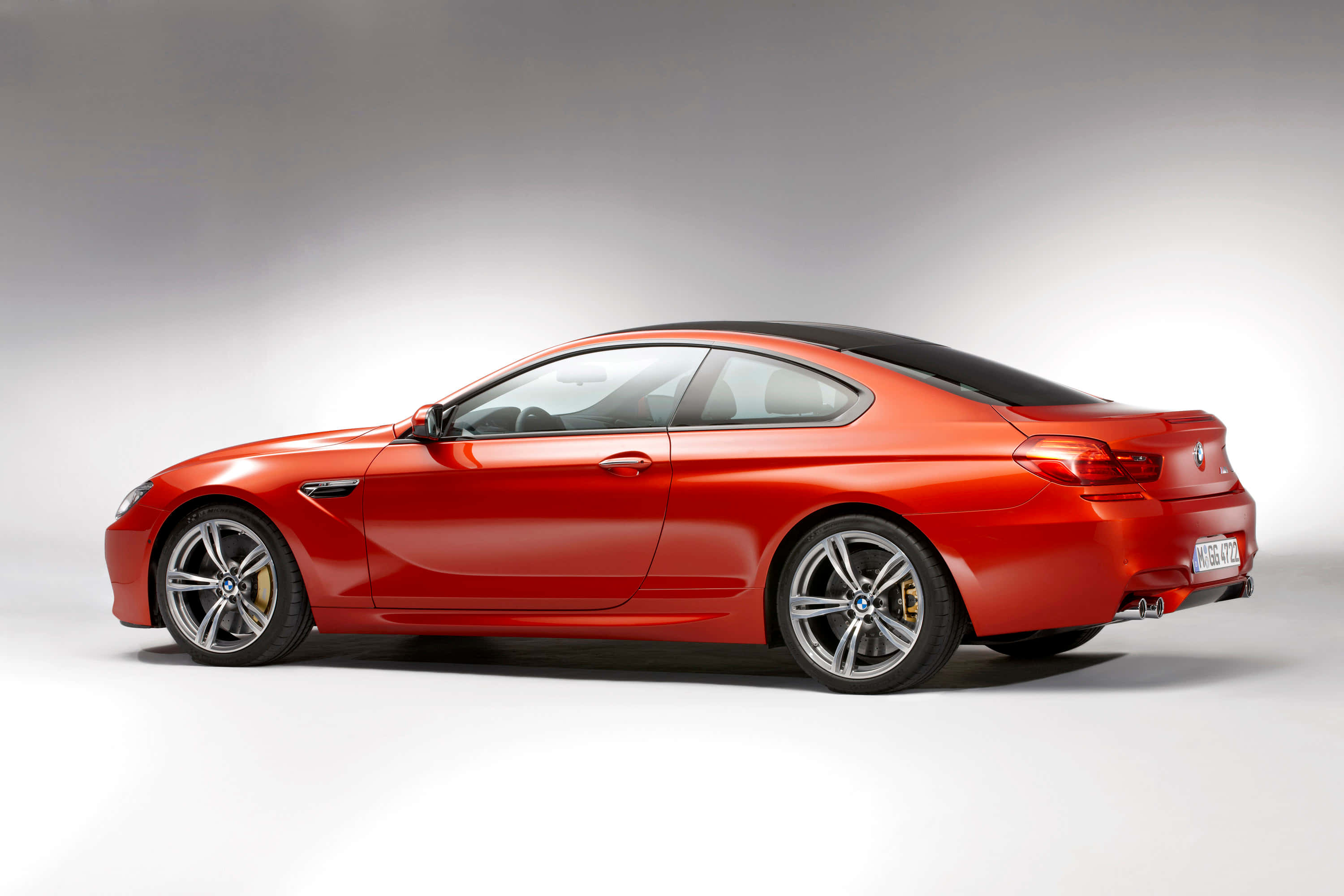 Bmw M6 桌布 壁紙 — 一輛時尚的紅色BMW M6雙門轎跑車，配備黑色車頂和金色制動卡鉗，在工作室側面展示。