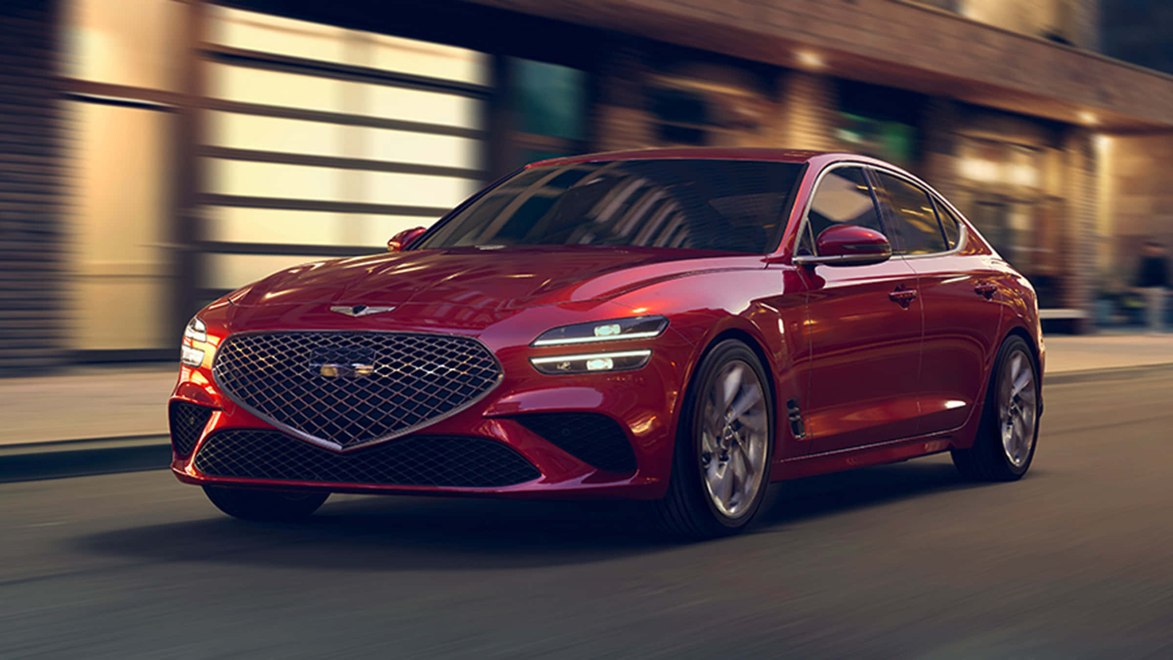 創世紀 桌布 壁紙 — 一輛時尚的紅色Genesis G70轎車在黃金時段疾馳穿過模糊的城市街道。