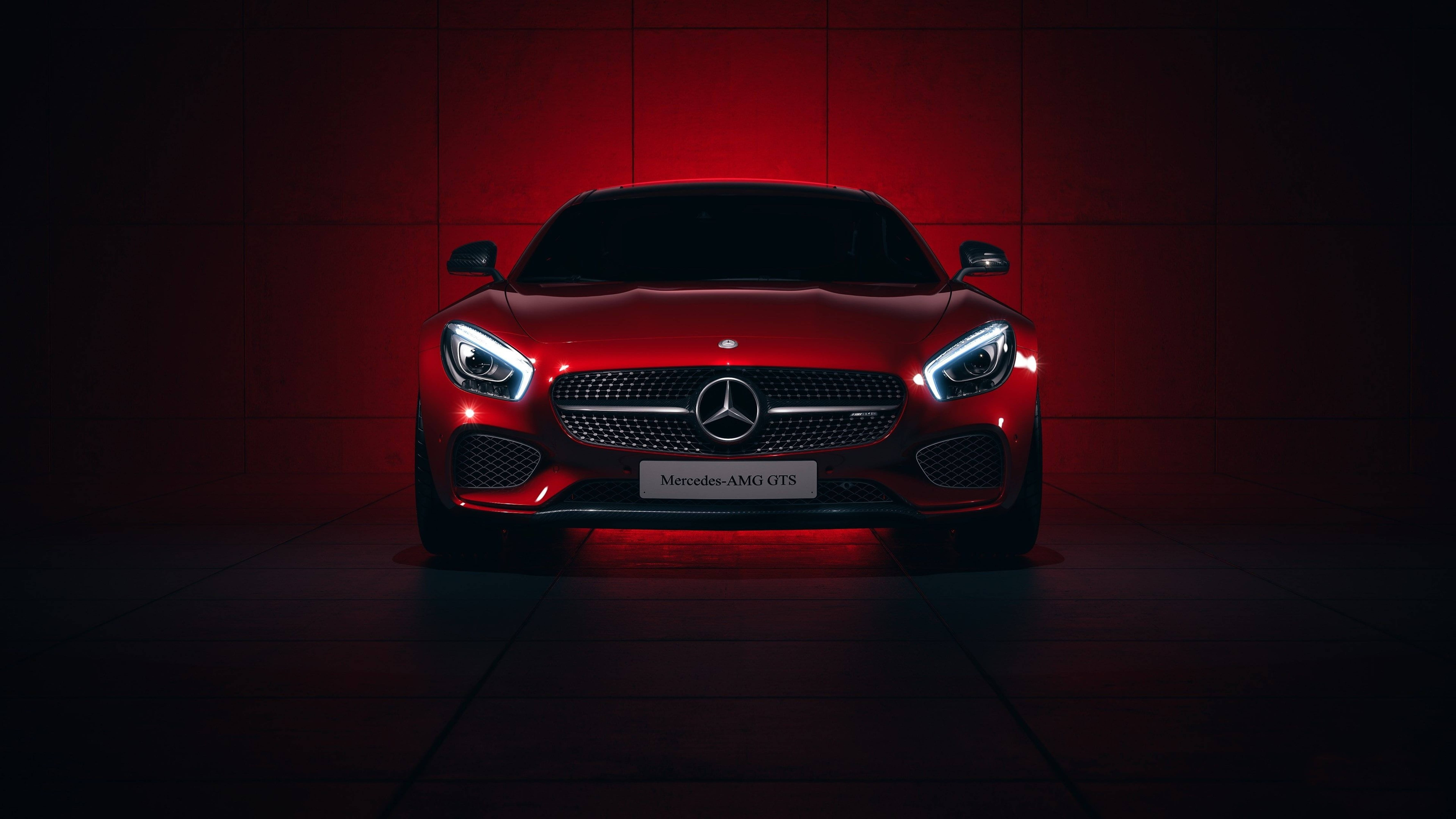 紅色動圖 桌布 壁紙 — 一輛時尚的紅色Mercedes-AMG GTS在戲劇性的紅色燈光下，在深色瓷磚牆前閃耀。