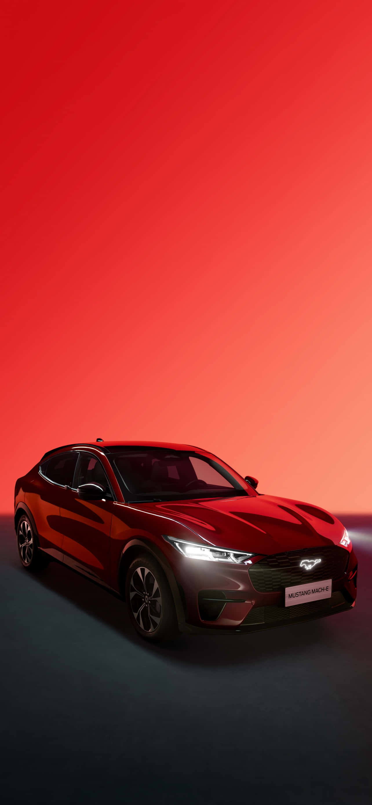 野馬GIF 桌布 壁紙 — 一輛時尚的紅色Mustang Mach-E電動SUV在戲劇性的漸變燈光下，在火紅的背景中閃耀。