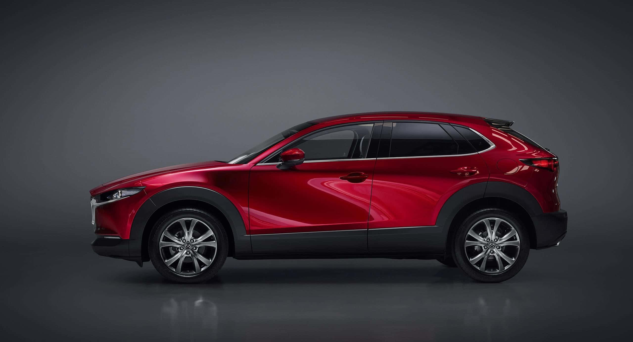 Mazda Cx-30 桌布 壁紙 — 一輛時尚的紅色SUV在攝影棚燈光下閃耀，背景為深灰色，地板上有微妙的倒影。