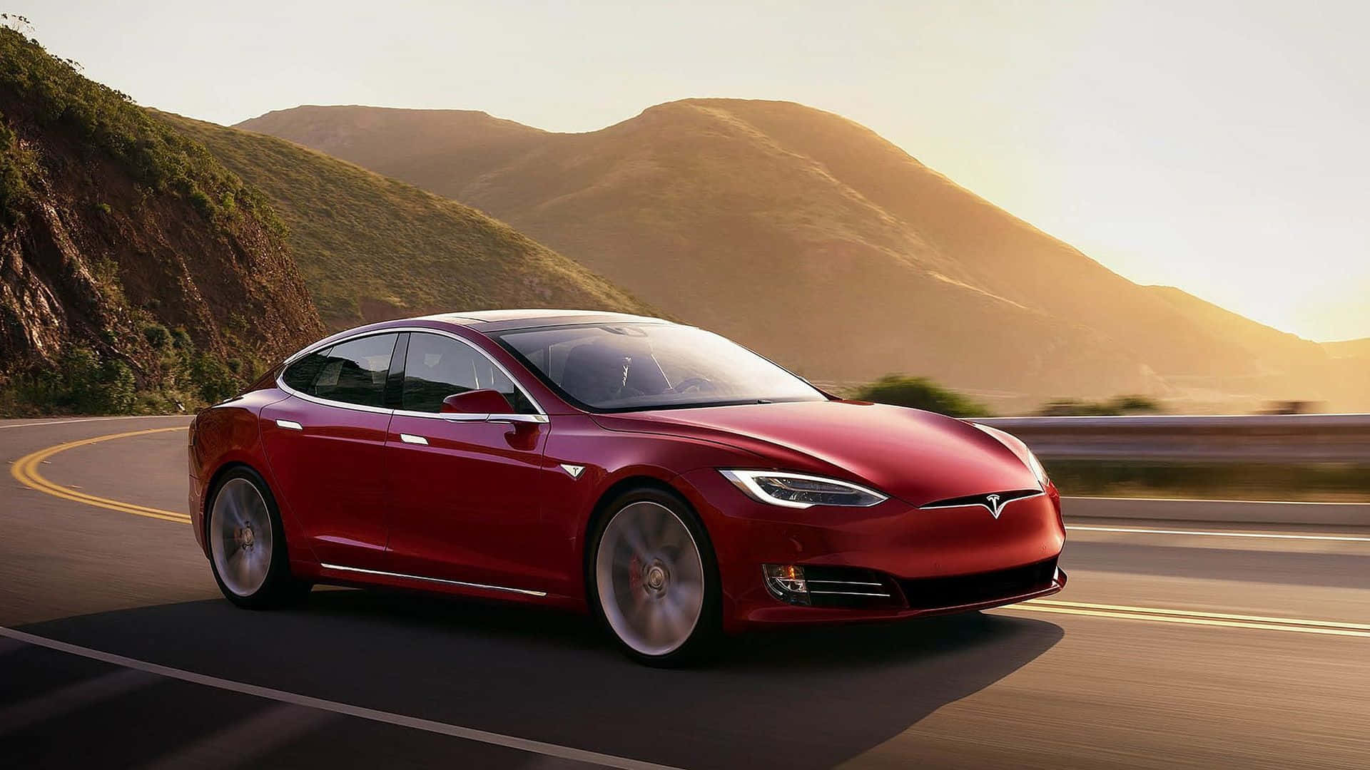 特斯拉 桌布 壁紙 — 一輛時尚的紅色Tesla Model S在蜿蜒的山路上巡航，沐浴在金色的夕陽光中。