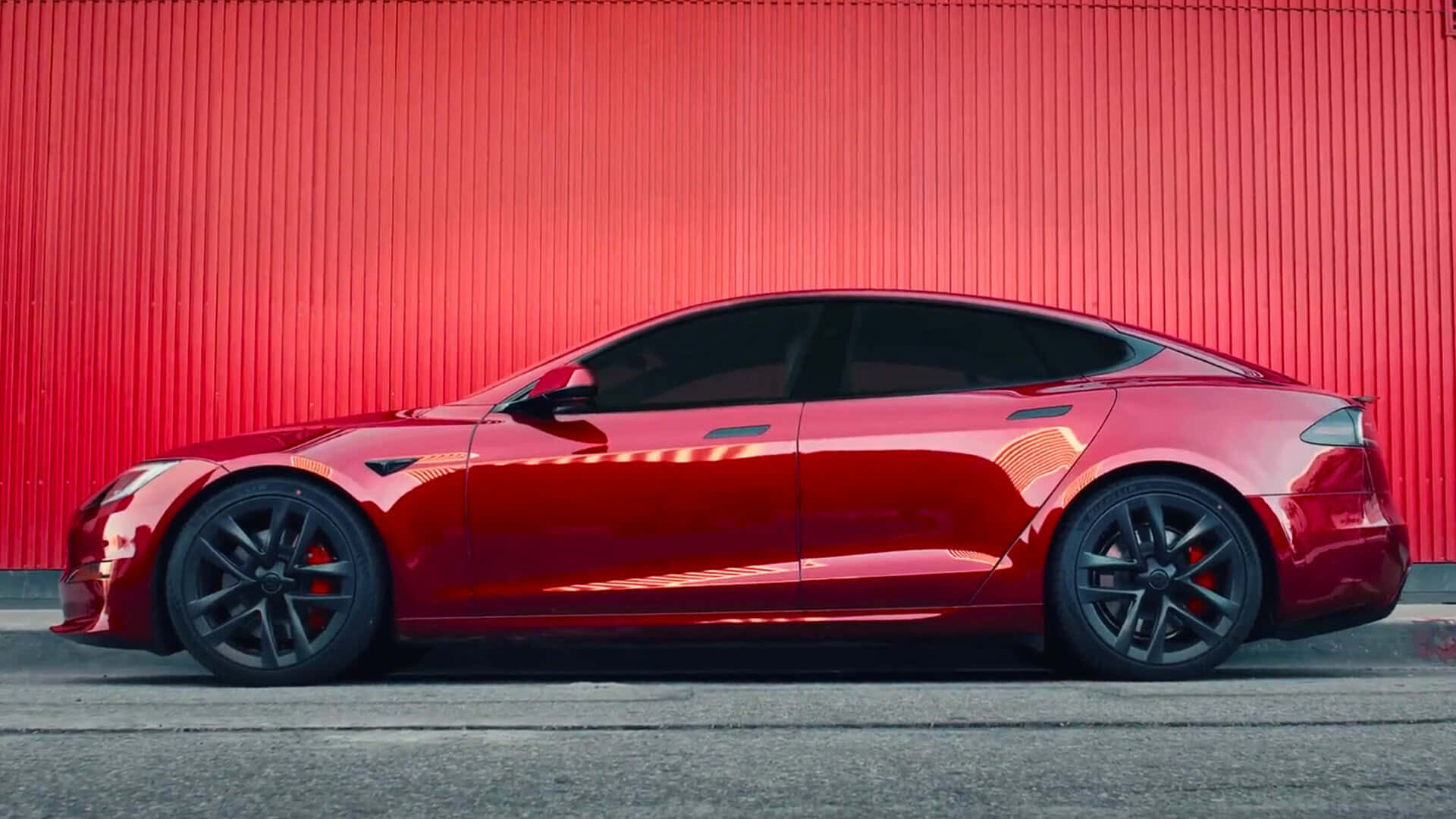 特斯拉 桌布 壁紙 — 一輛時尚的紅色Tesla Model S跑車停在一面充滿活力的紅色波紋金屬牆前。