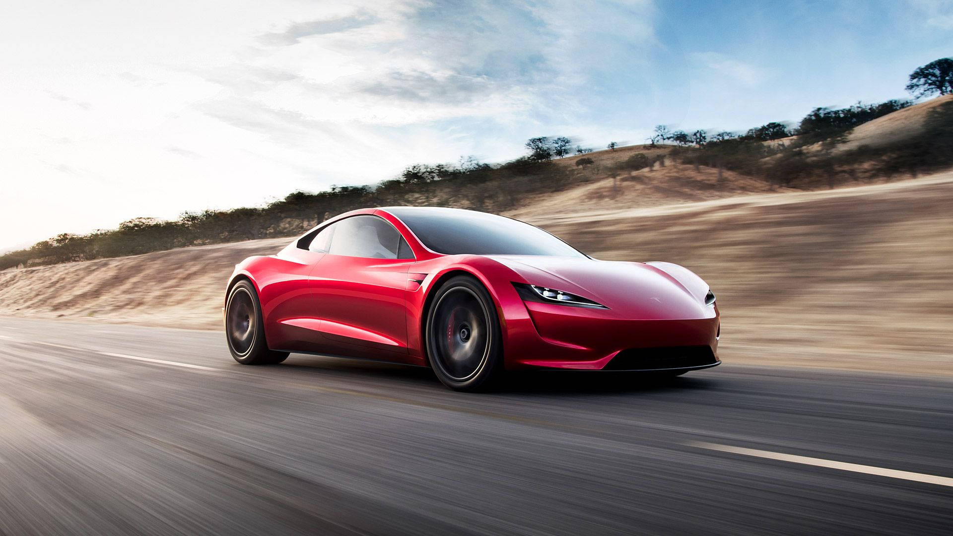 特斯拉 桌布 壁紙 — 一輛時尚的紅色Tesla Roadster在沙漠公路上疾馳，天空湛藍，白雲點點。
