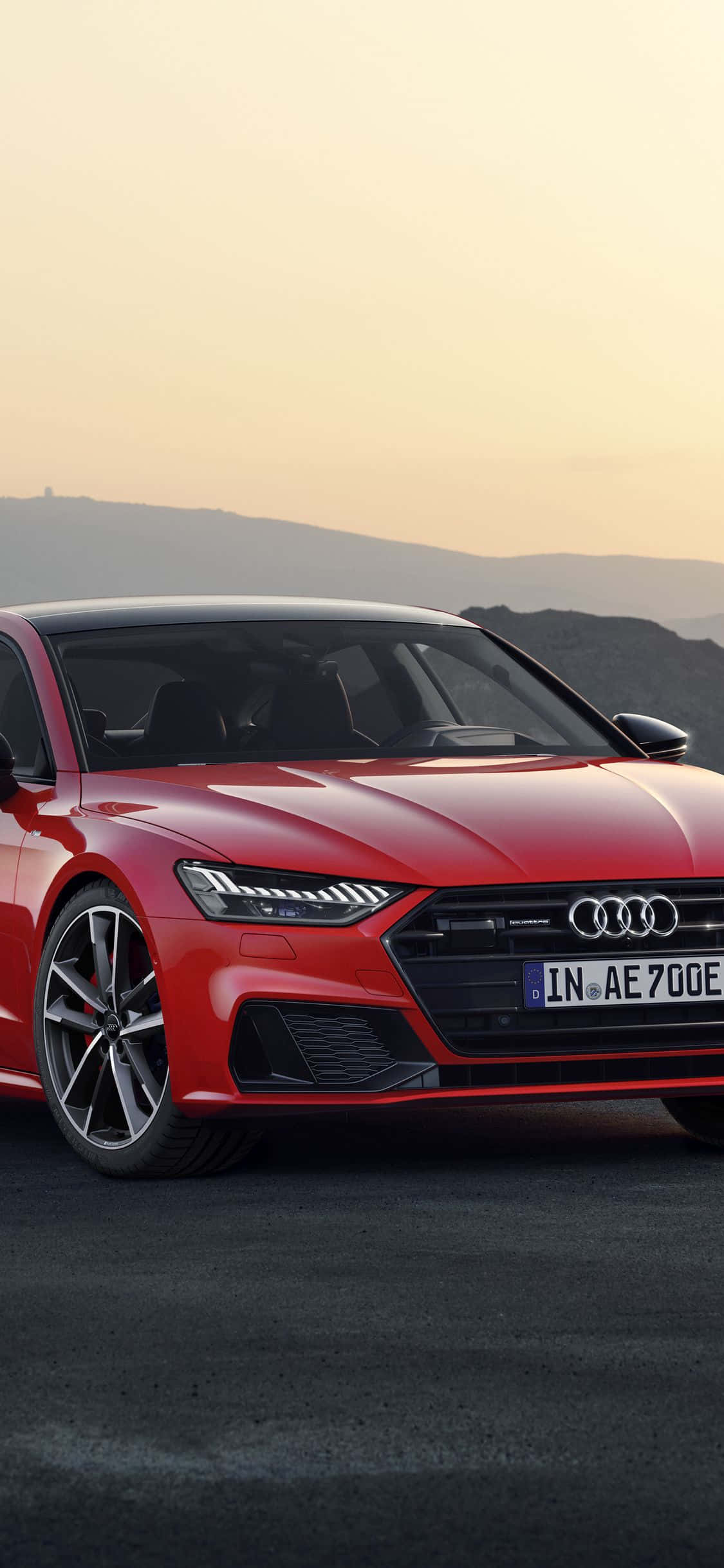 Audi S7 桌布 壁紙 — 一輛時尚的紅色奧迪跑車在黃金時段停泊在瀝青路上，背景是山脈。