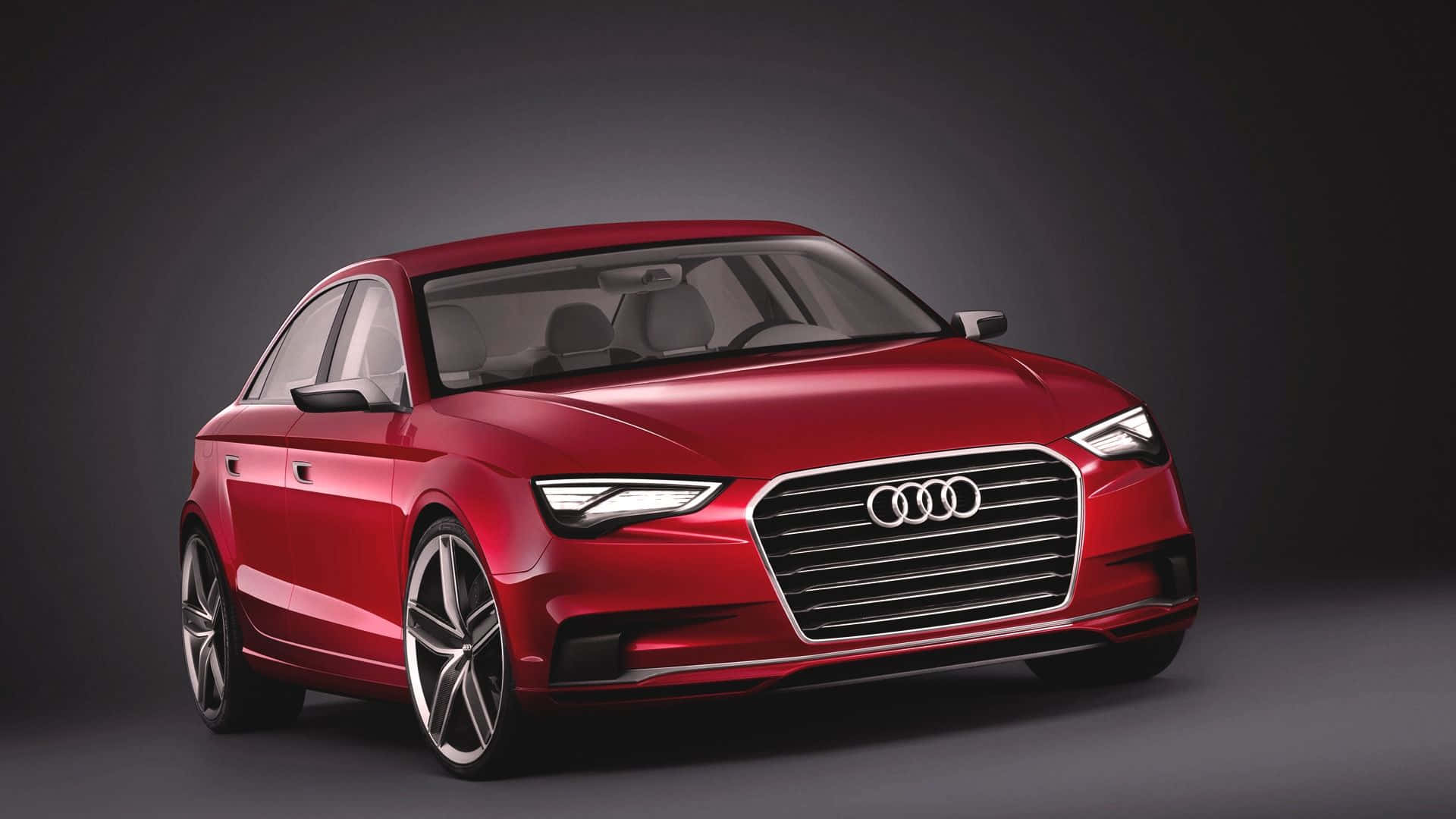 Audi A3 桌布 壁紙 — 一輛時尚的紅色奧迪轎車在攝影棚燈光下，在深色漸變背景上閃閃發光。