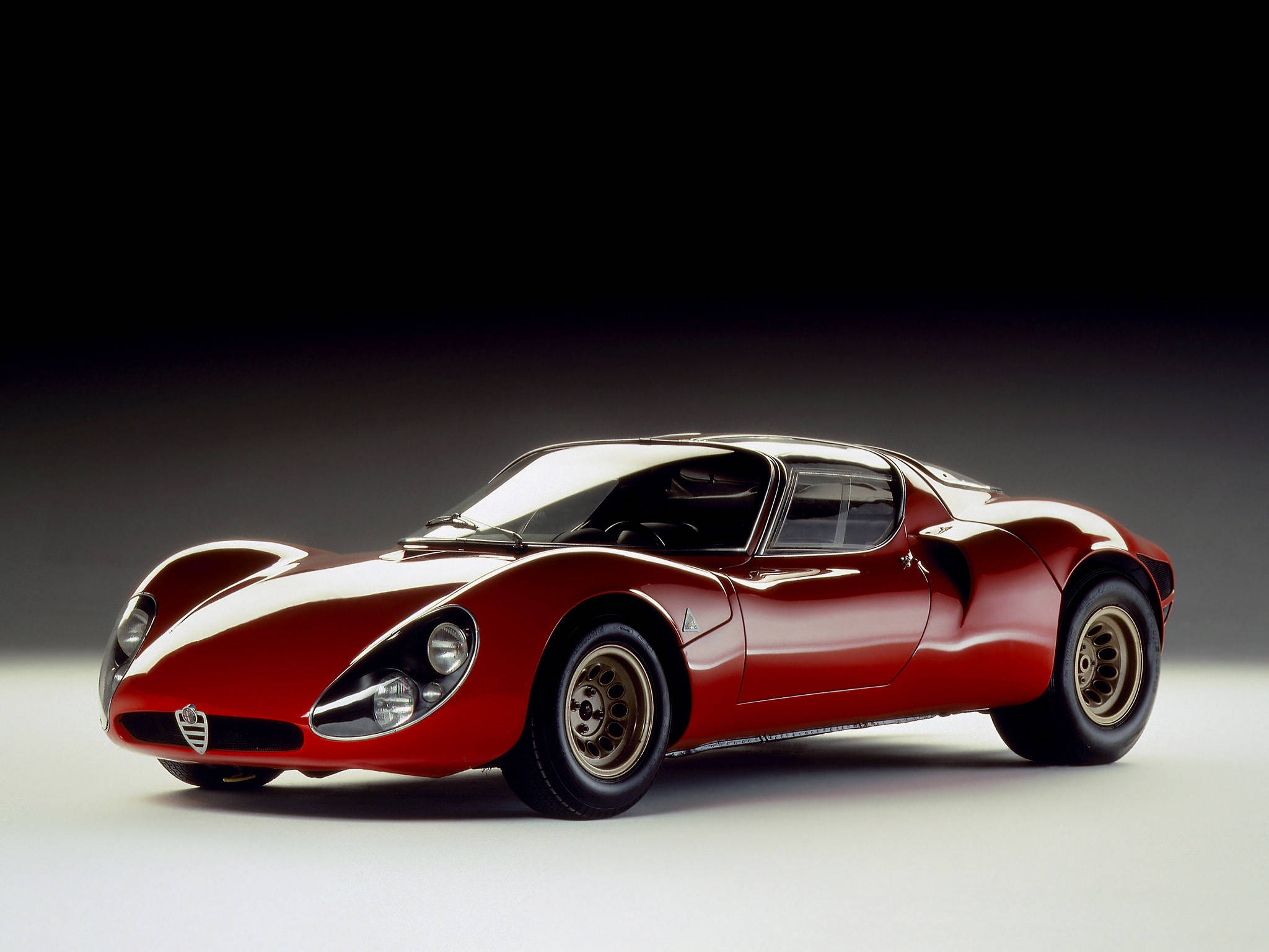alfa romeo iPhone 桌布 壁紙 — 一輛時尚的紅色復古賽車，帶有白色點綴和金色輪圈，擺放在深色漸變背景前。