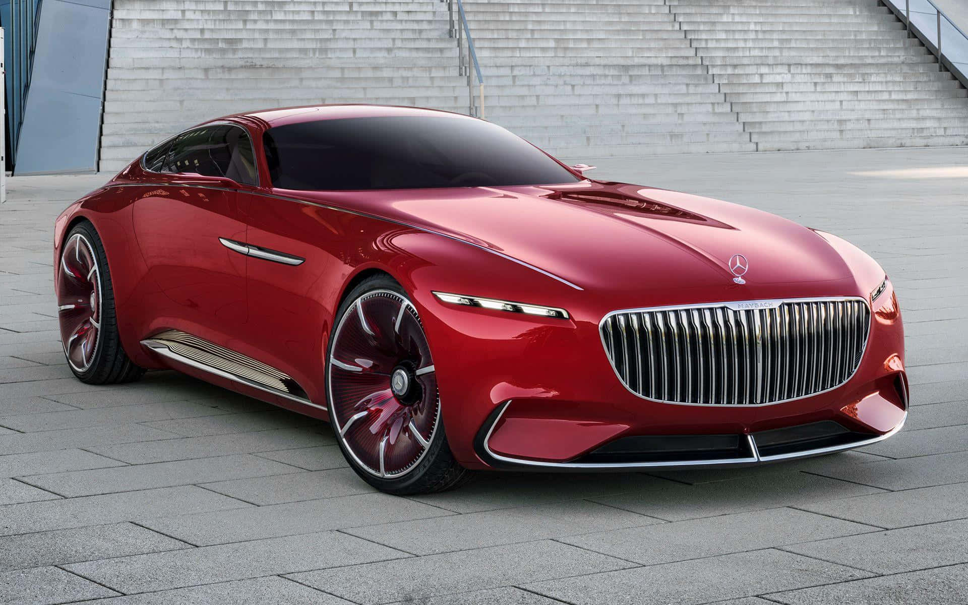 Maybach 桌布 壁紙 — 一輛時尚的紅色梅賽德斯-奔馳概念車在日光下閃耀，背景是現代石質廣場和寬闊的樓梯。