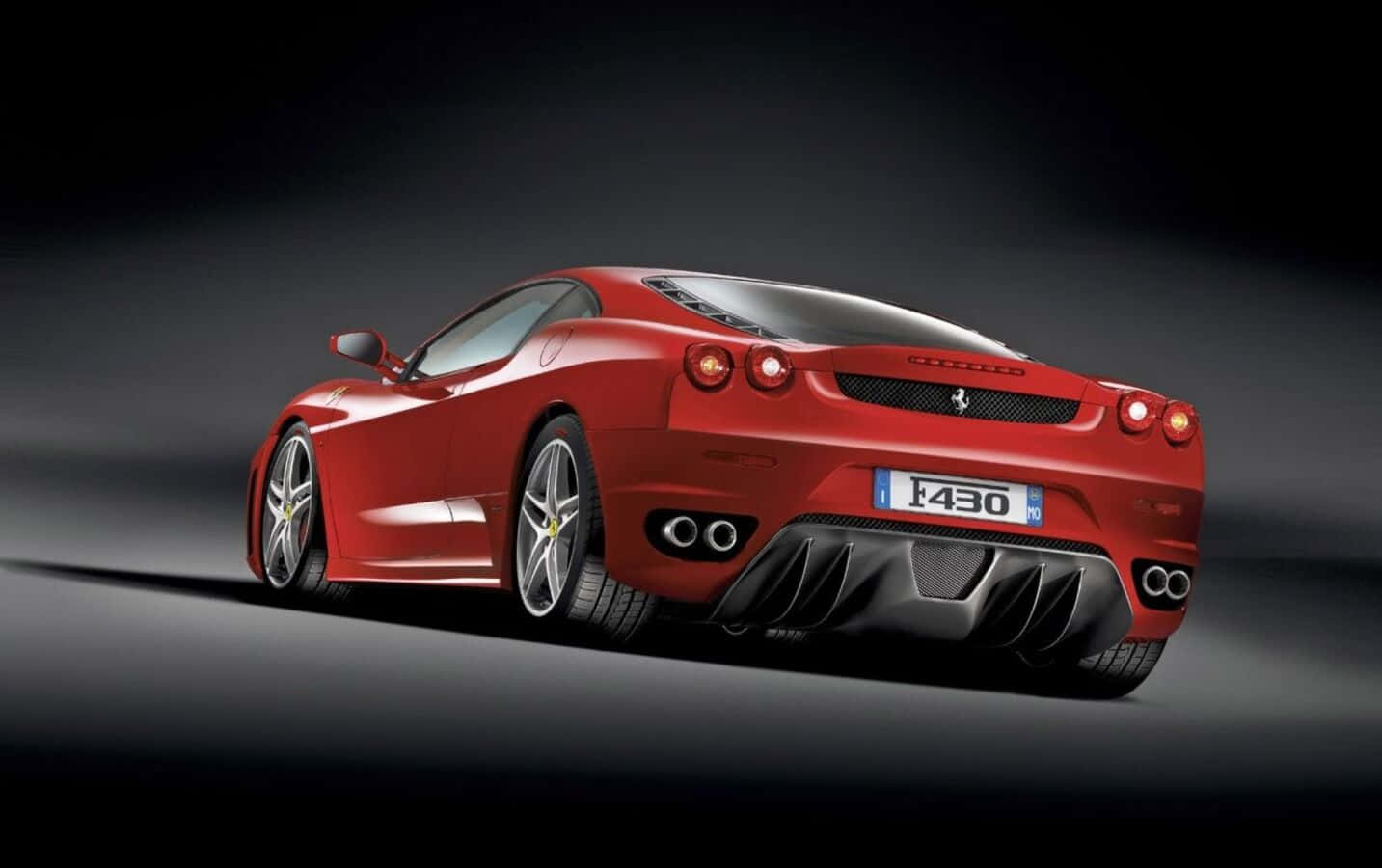 Ferrari F430 桌布 壁紙 — 一輛時尚的紅色法拉利F430跑車在攝影棚燈光下，在深色漸變背景上閃耀。