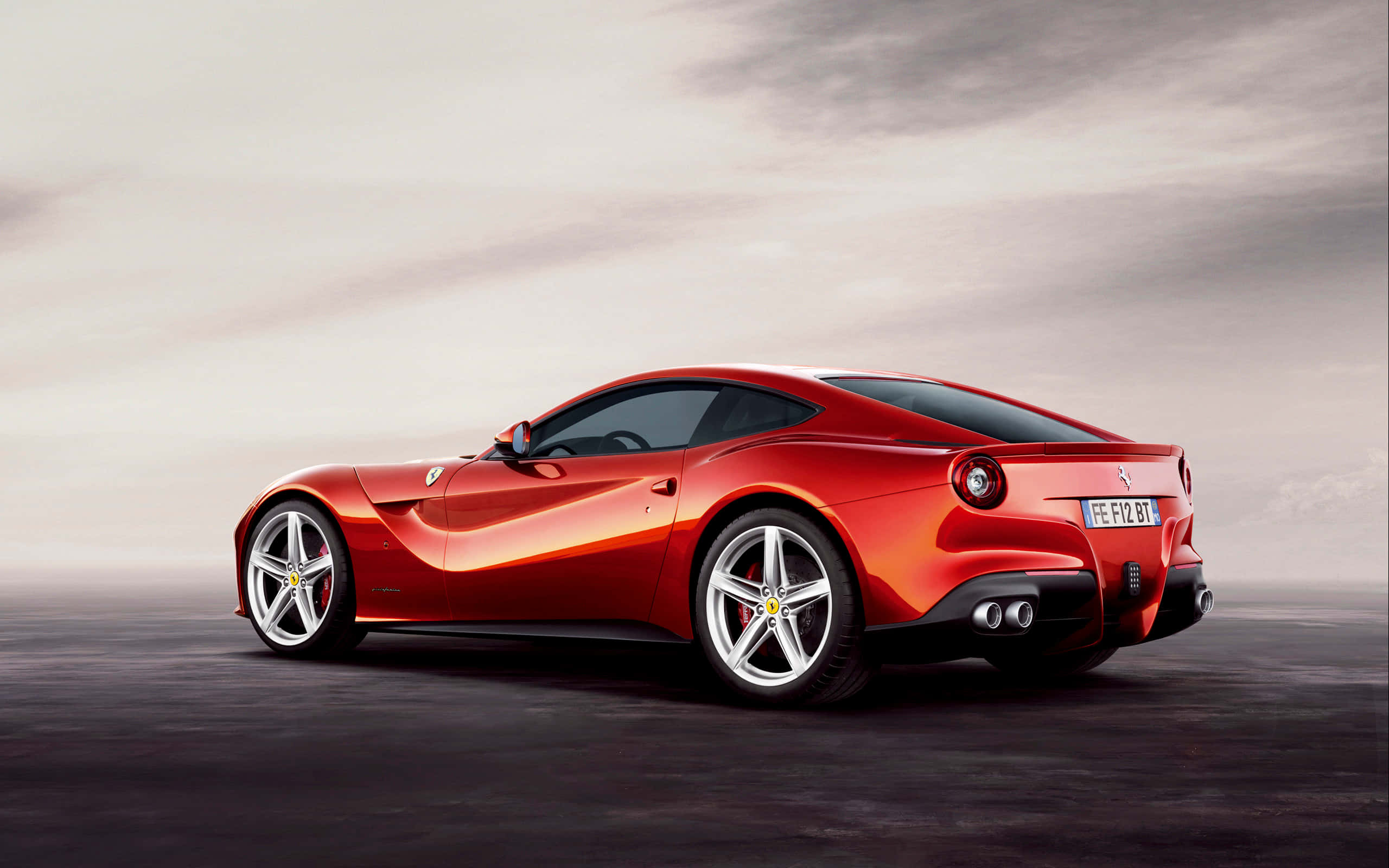 Ferrari F12 Berlinetta 桌布 壁紙 — 一輛時尚的紅色法拉利跑車在陰天之下，在極簡的灰色表面上閃閃發光。