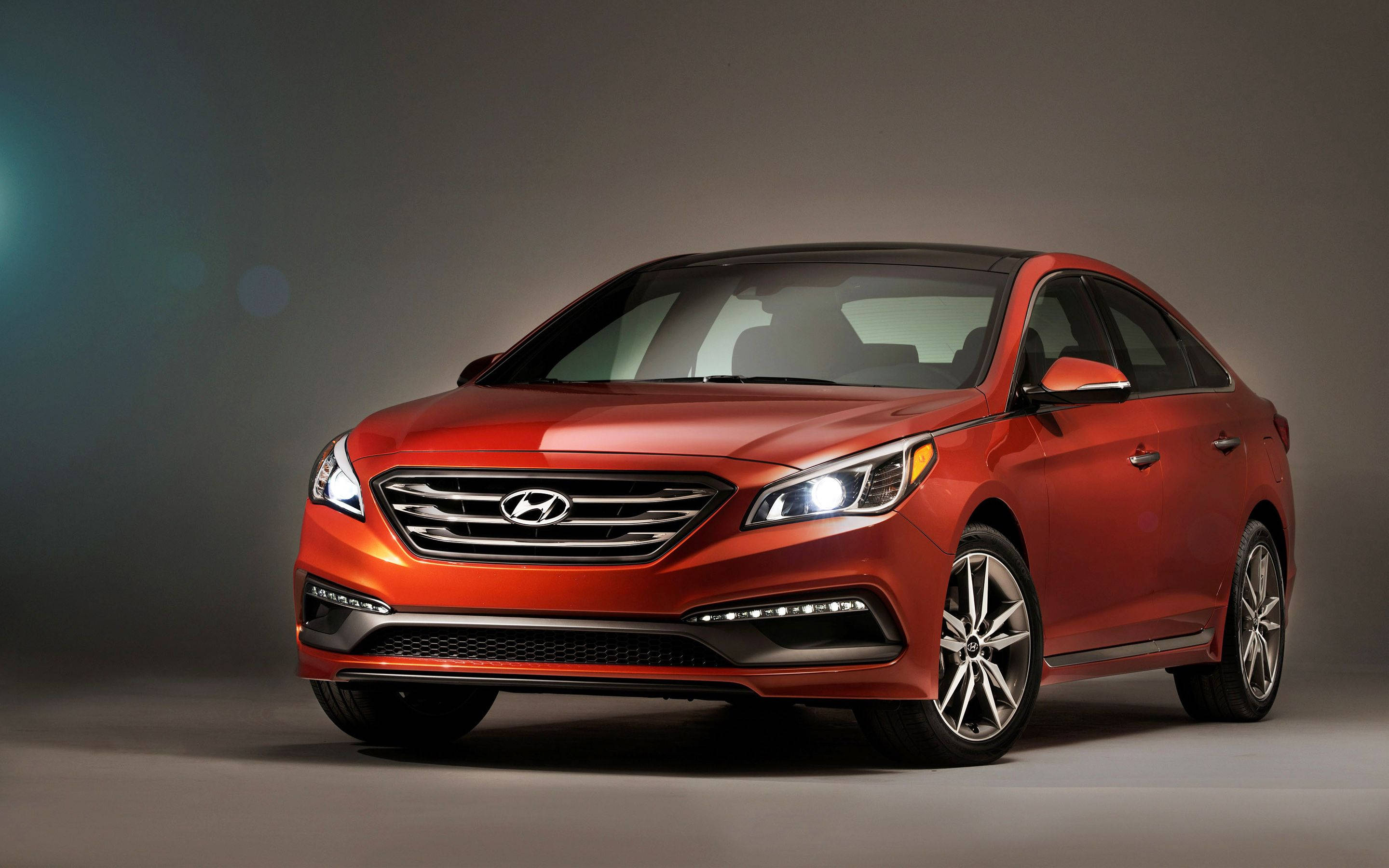Hyundai 桌布 壁紙 — 一輛時尚的紅色現代轎車在攝影棚燈光下閃耀，線條銳利，車頭燈發光，背景為柔和的灰色。