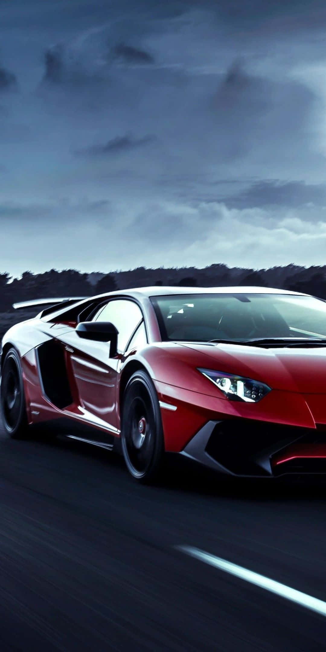 Pixel 3 Lamborghini 桌布 壁紙 — 一輛時尚的紅色藍寶堅尼 Aventador 在暴風雨黃昏的天空下，沿著黑暗的道路飛馳。