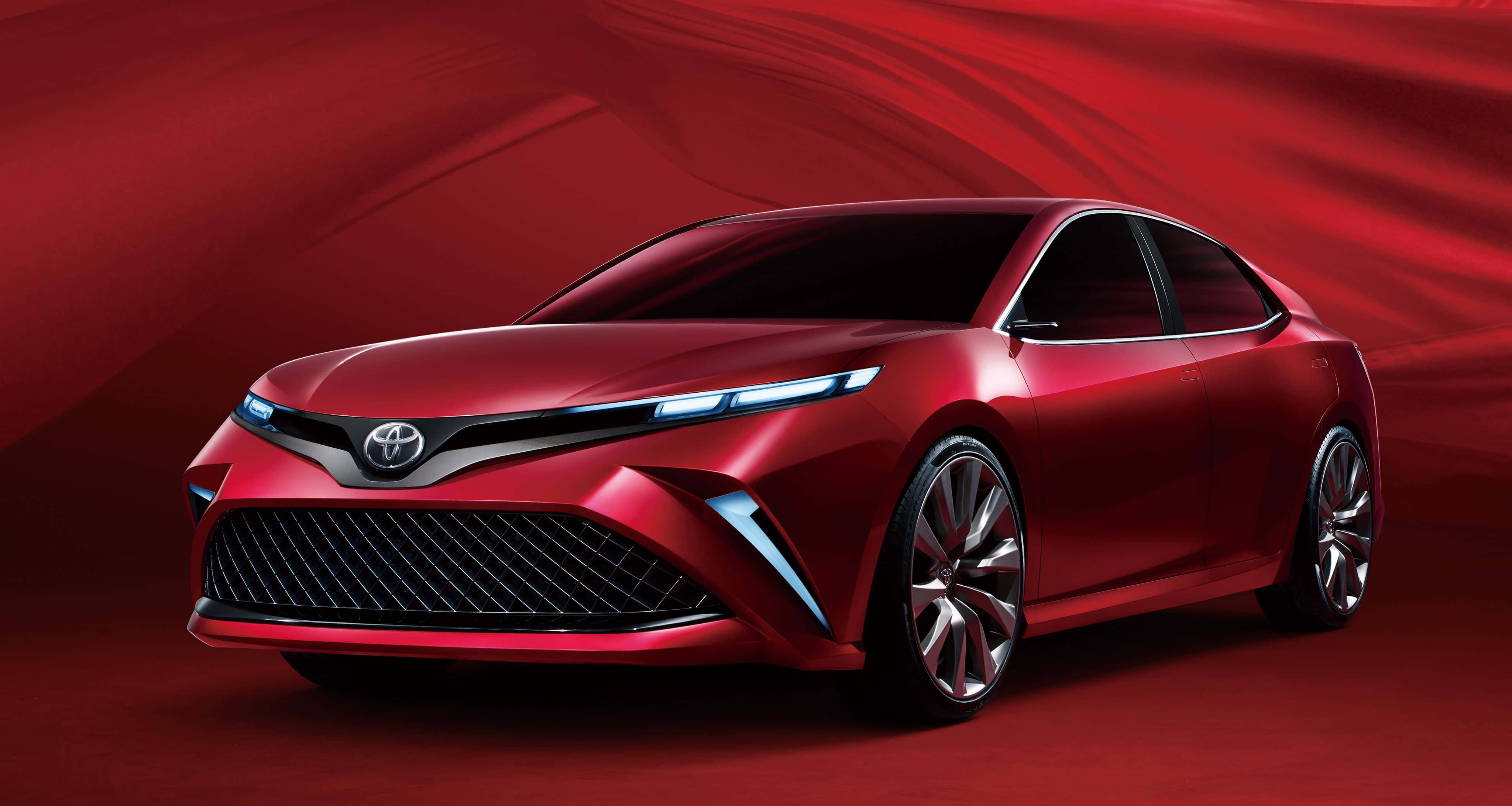 Toyota 桌布 壁紙 — 一輛時尚的紅色豐田概念車，帶有發光的藍色車頭燈，矗立在流動的深紅色背景前。