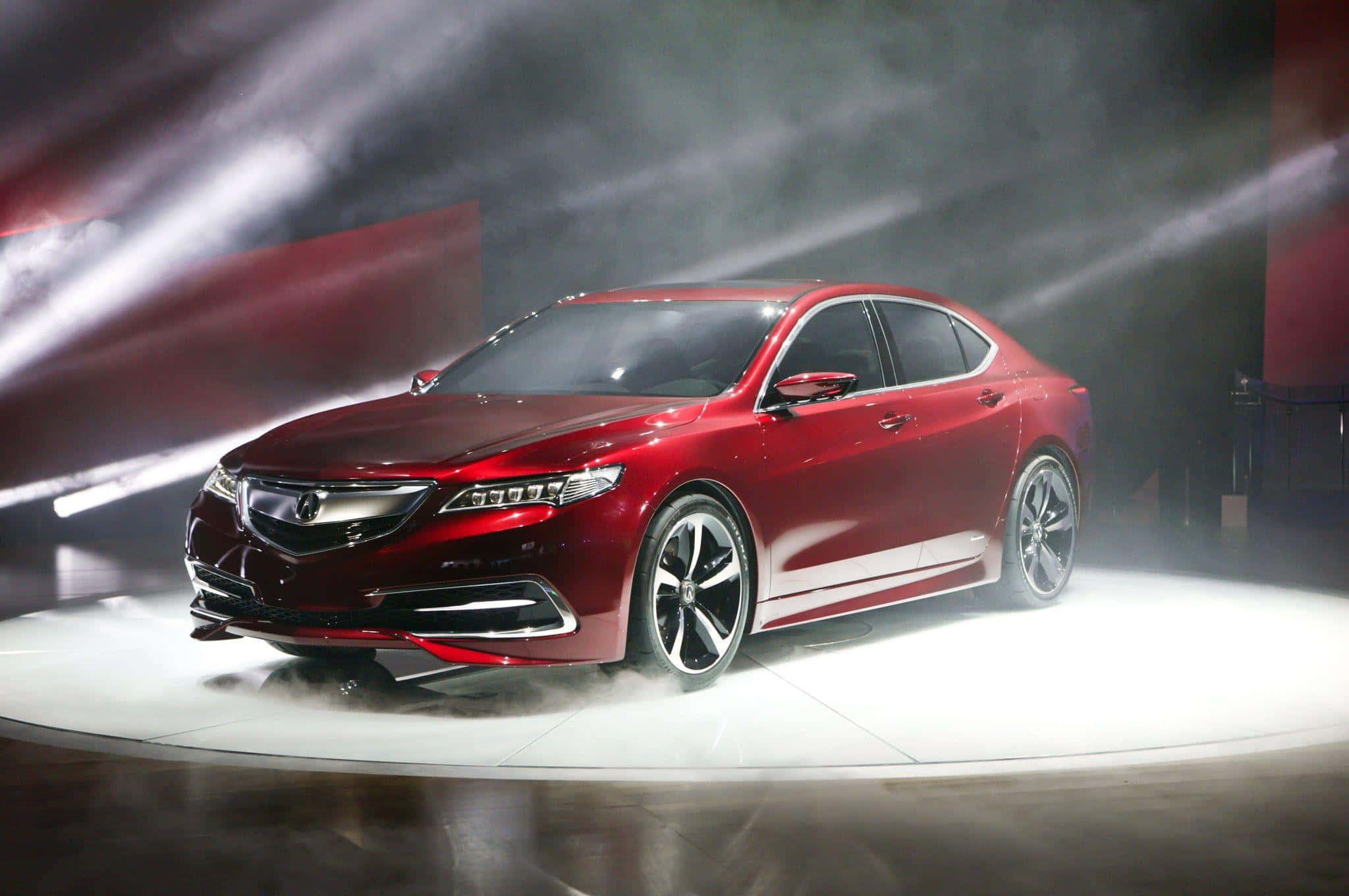 Acura Tlx 桌布 壁紙 — 一輛時尚的紅色豪華轎車在車展的煙霧繚繞圓形舞台上，在戲劇性的聚光燈下閃閃發光。