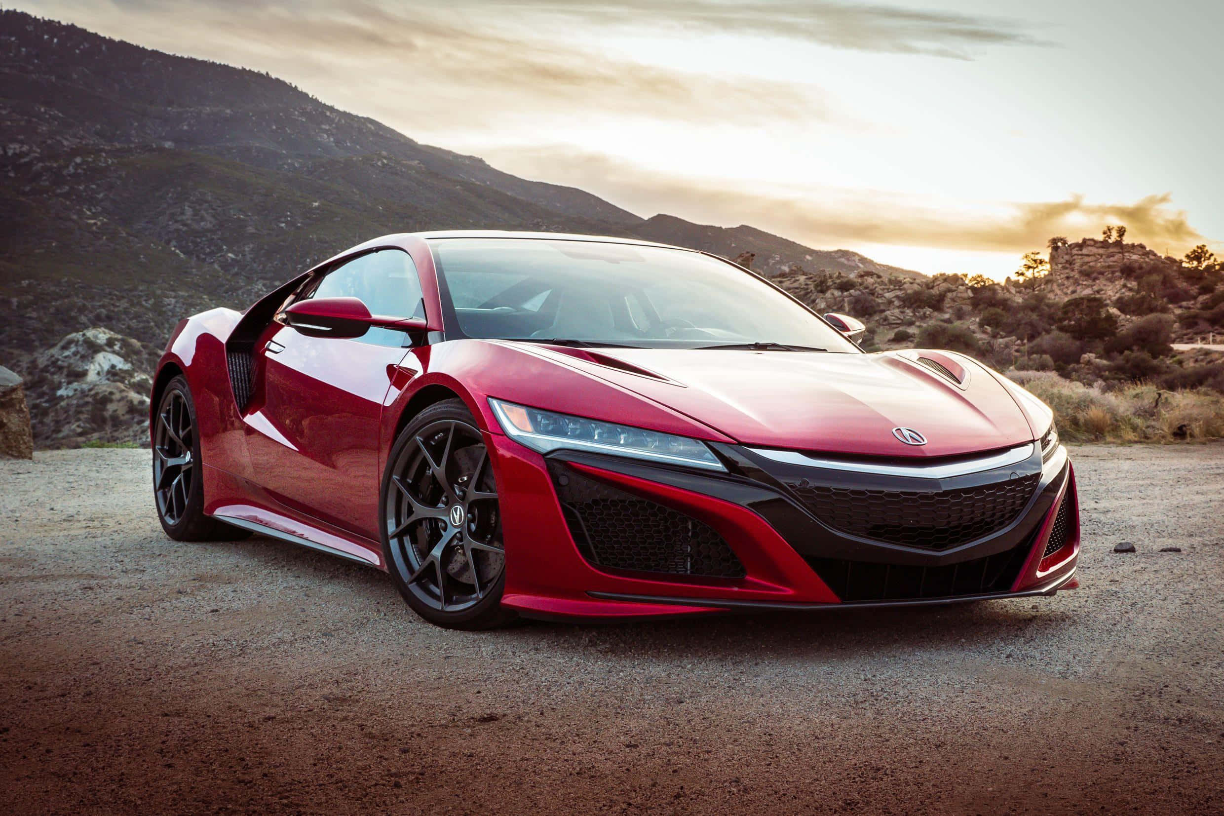 Acura Nsx 桌布 壁紙 — 一輛時尚的紅色跑車停泊在碎石路上，背景是日落時分的山脈。
