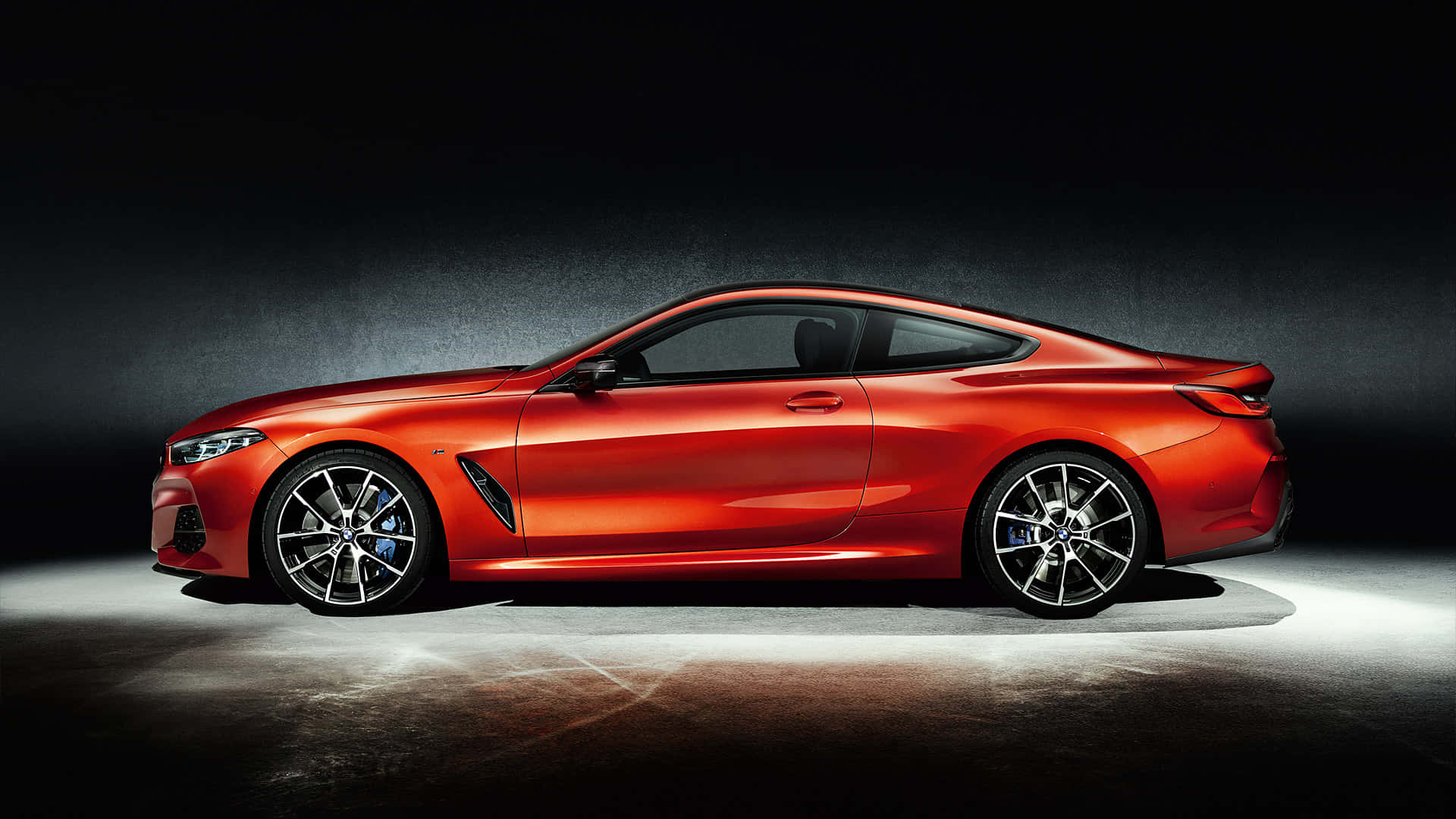 BMW 動圖 桌布 壁紙 — 一輛時尚的紅色跑車在戲劇性的攝影棚燈光下，以深色紋理背景襯托，閃閃發光。
