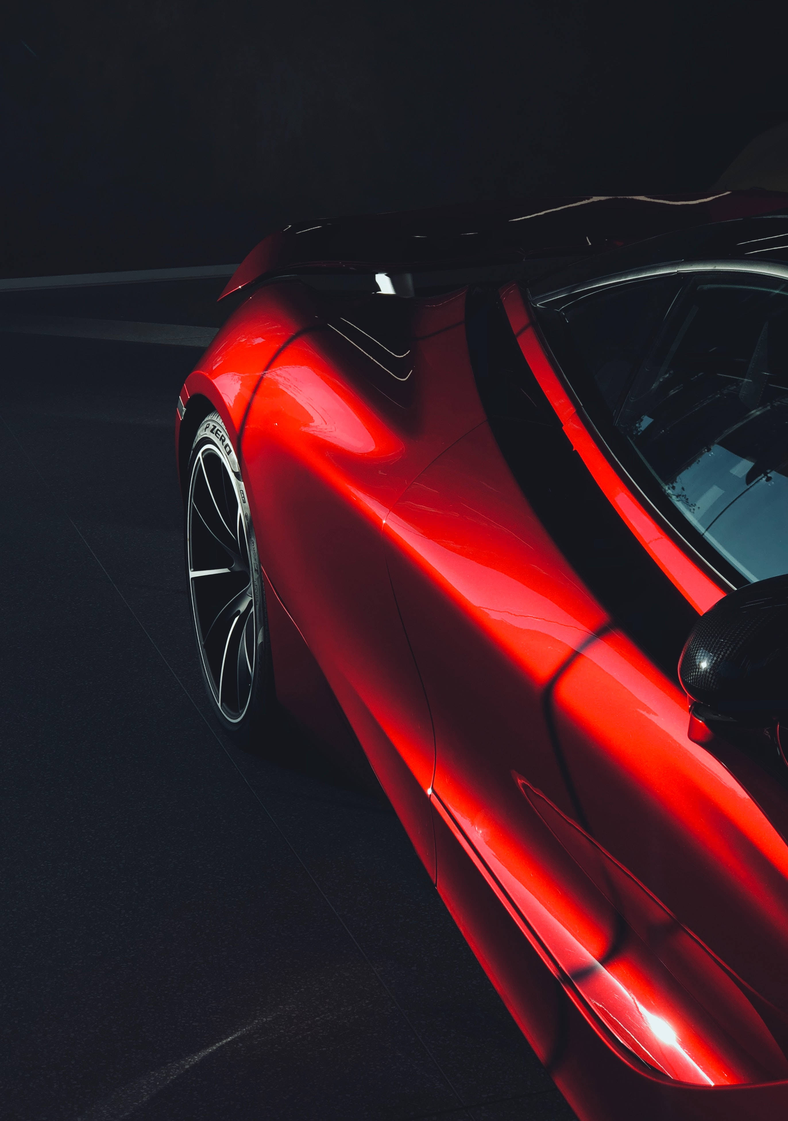 Mclaren 720s 桌布 壁紙 — 一輛時尚的紅色跑車在黑暗的攝影棚地板上，在戲劇性的燈光下閃耀。