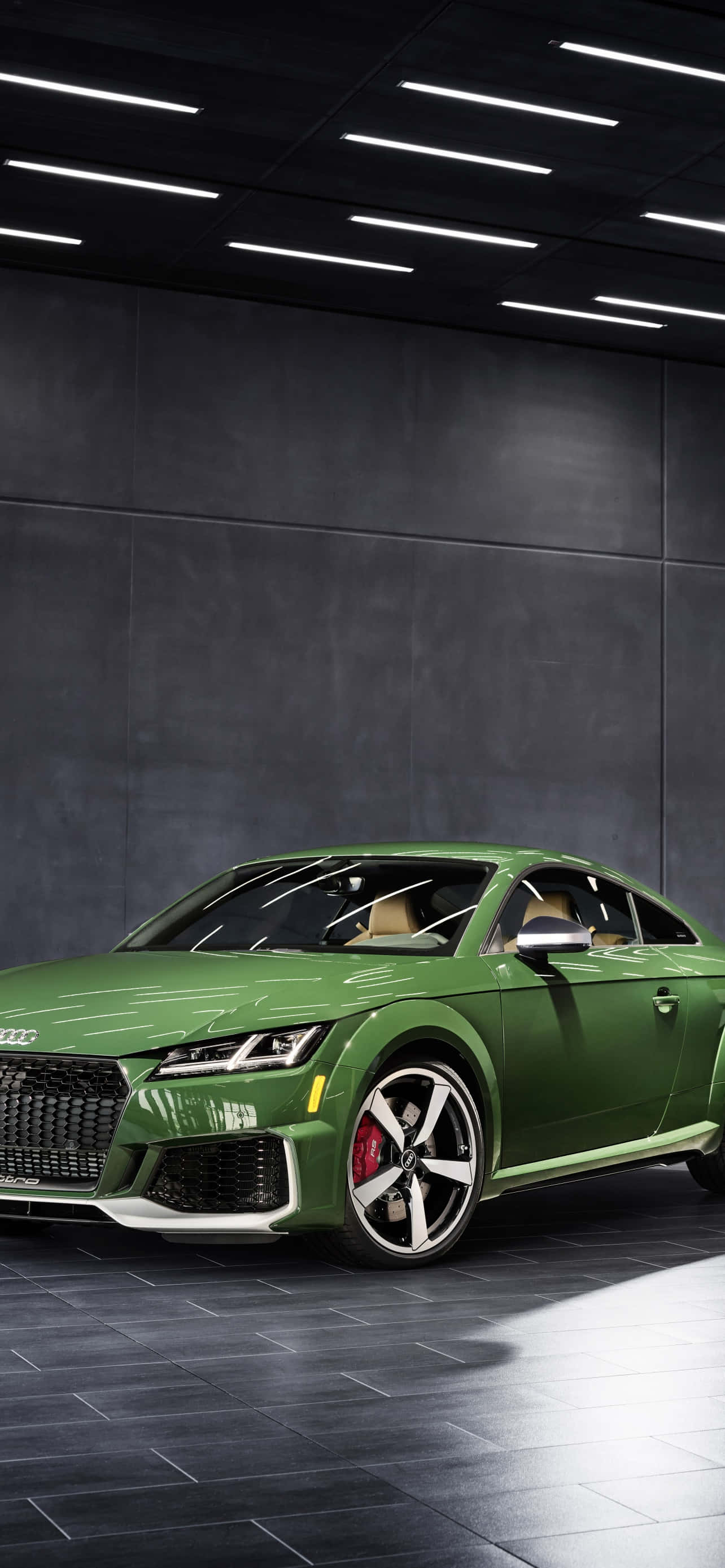 Audi Tt Rs 桌布 壁紙 — 一輛時尚的綠色奧迪TT RS轎跑車在簡約深灰色瓷磚車庫中，在明亮的天花板燈光下閃閃發光。