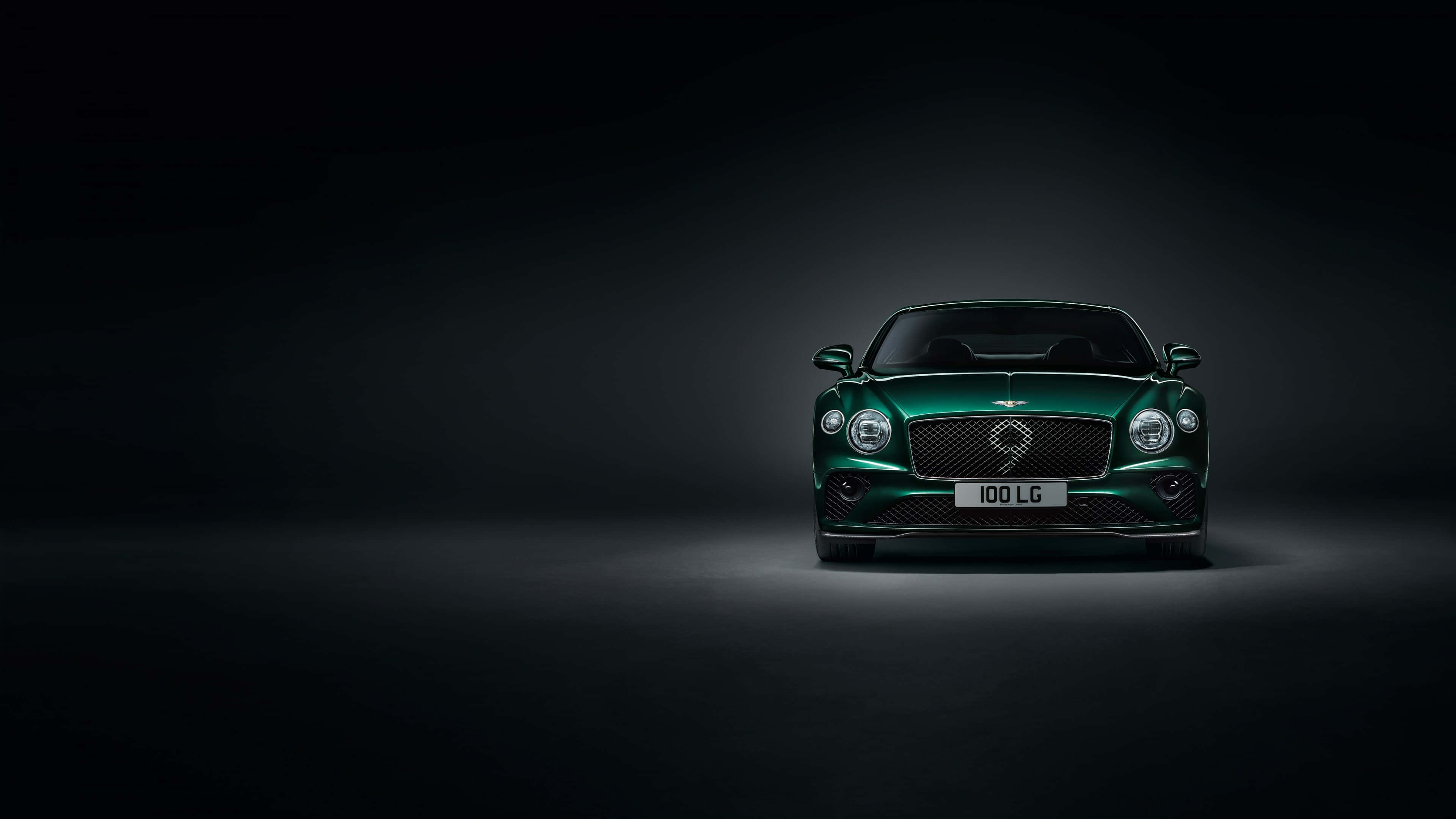 桌布 壁紙 — 一輛時尚的綠色賓利 Continental GT 在黑暗的攝影棚背景下，於戲劇性的聚光燈下閃閃發光。