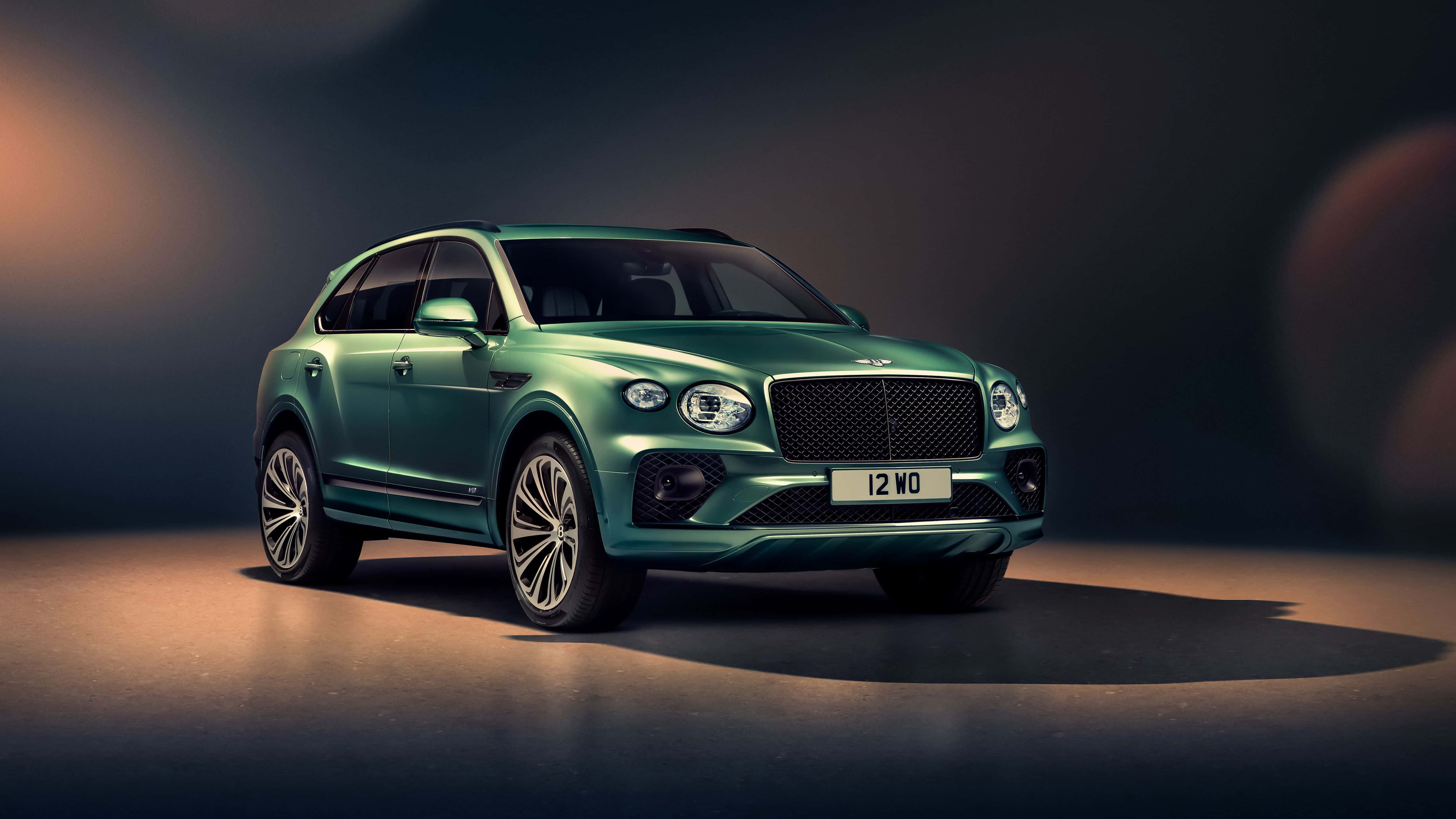 Bentley Bentayga 桌布 壁紙 — 一輛時尚的綠色賓利Bentayga SUV在戲劇性的攝影棚燈光下閃耀，投射出溫暖的高光和深邃的陰影。