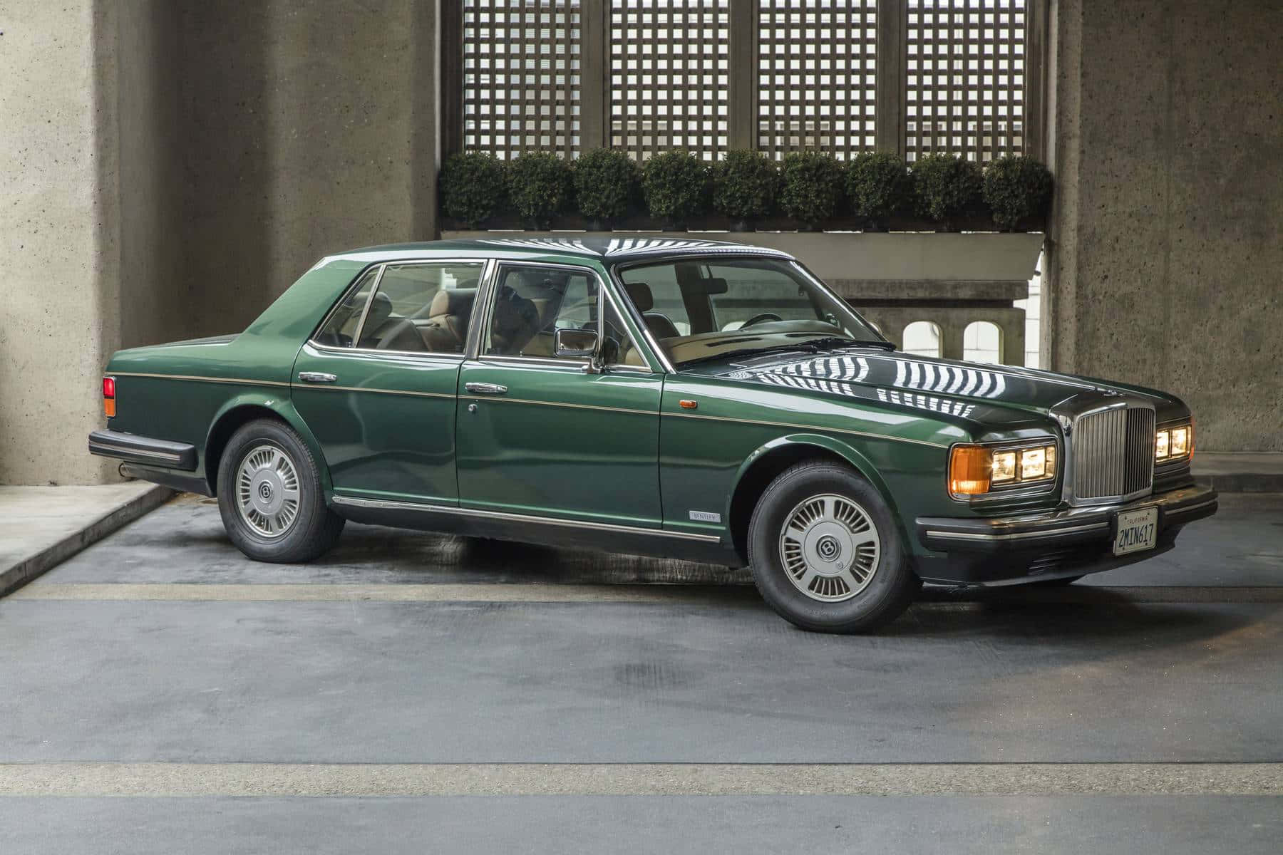 Bentley Eight 桌布 壁紙 — 一輛時尚的綠色賓利轎車，帶有鍍鉻飾邊，停在帶有格柵窗的混凝土結構下。