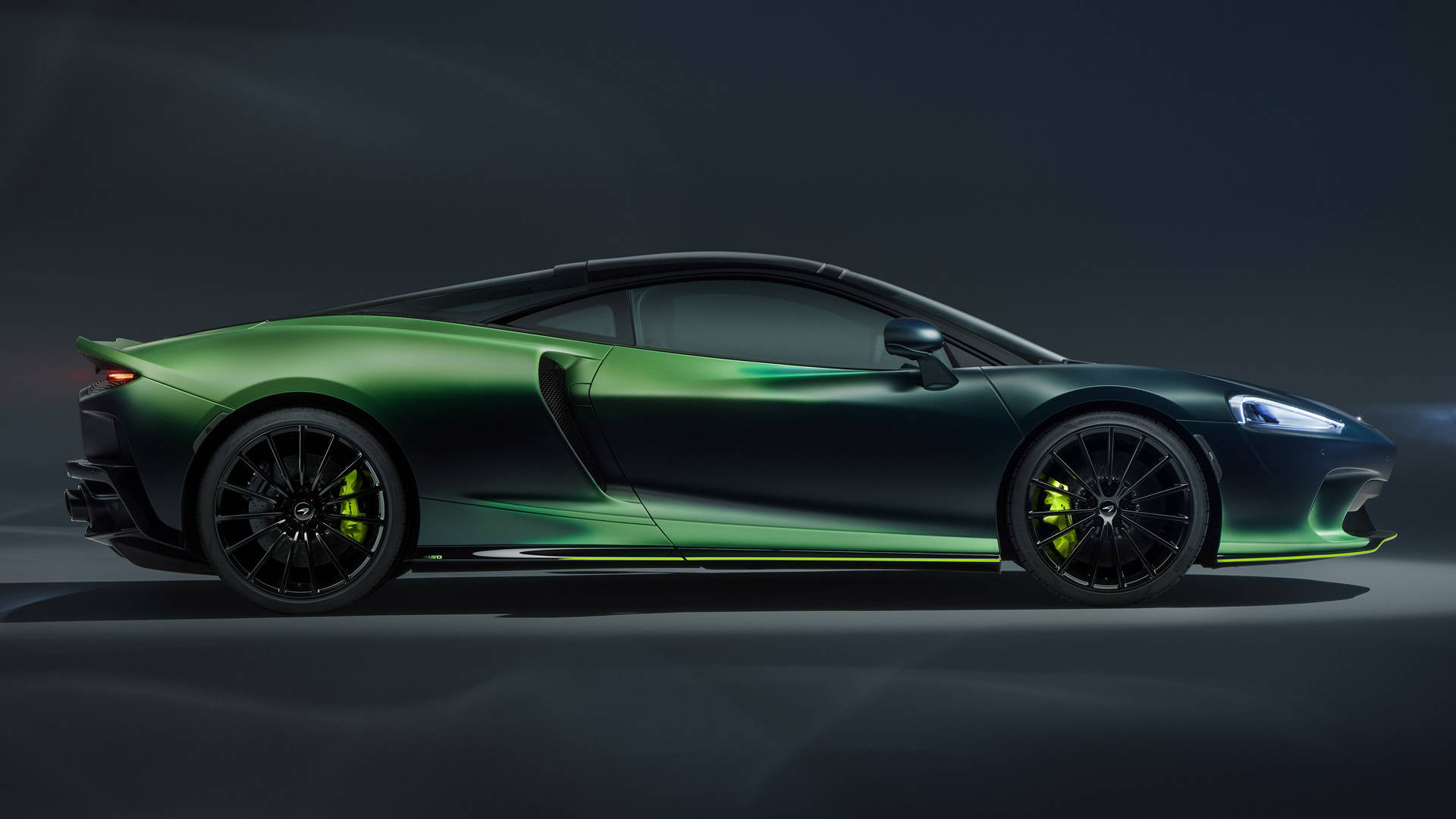 Cool Car 桌布 壁紙 — 一輛時尚的綠色跑車，帶有黑色飾邊和黃色制動卡鉗，在戲劇性的工作室燈光下滑行。