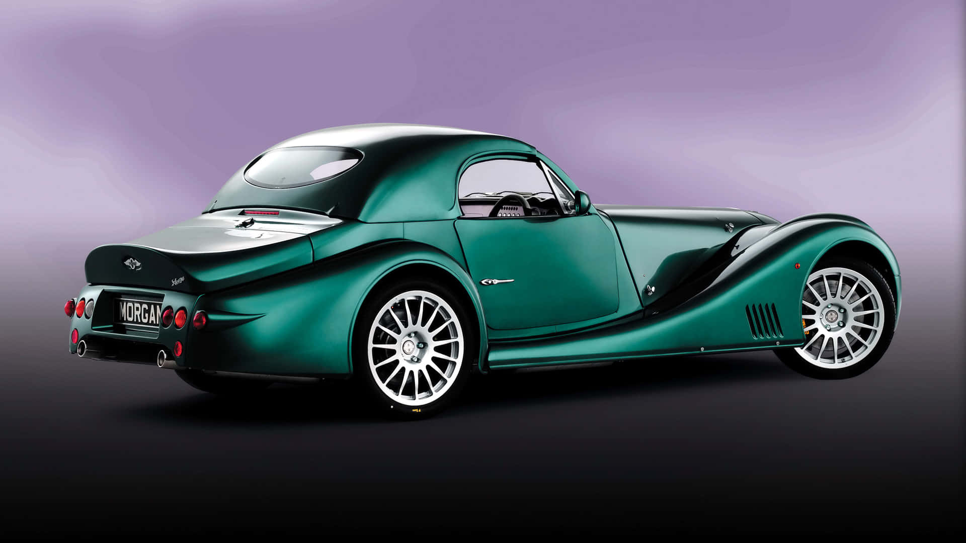 Morgan 桌布 壁紙 — 一輛時尚的翠綠色摩根跑車配備銀色輪圈，在紫色和黑色漸變背景的攝影棚環境中展示。