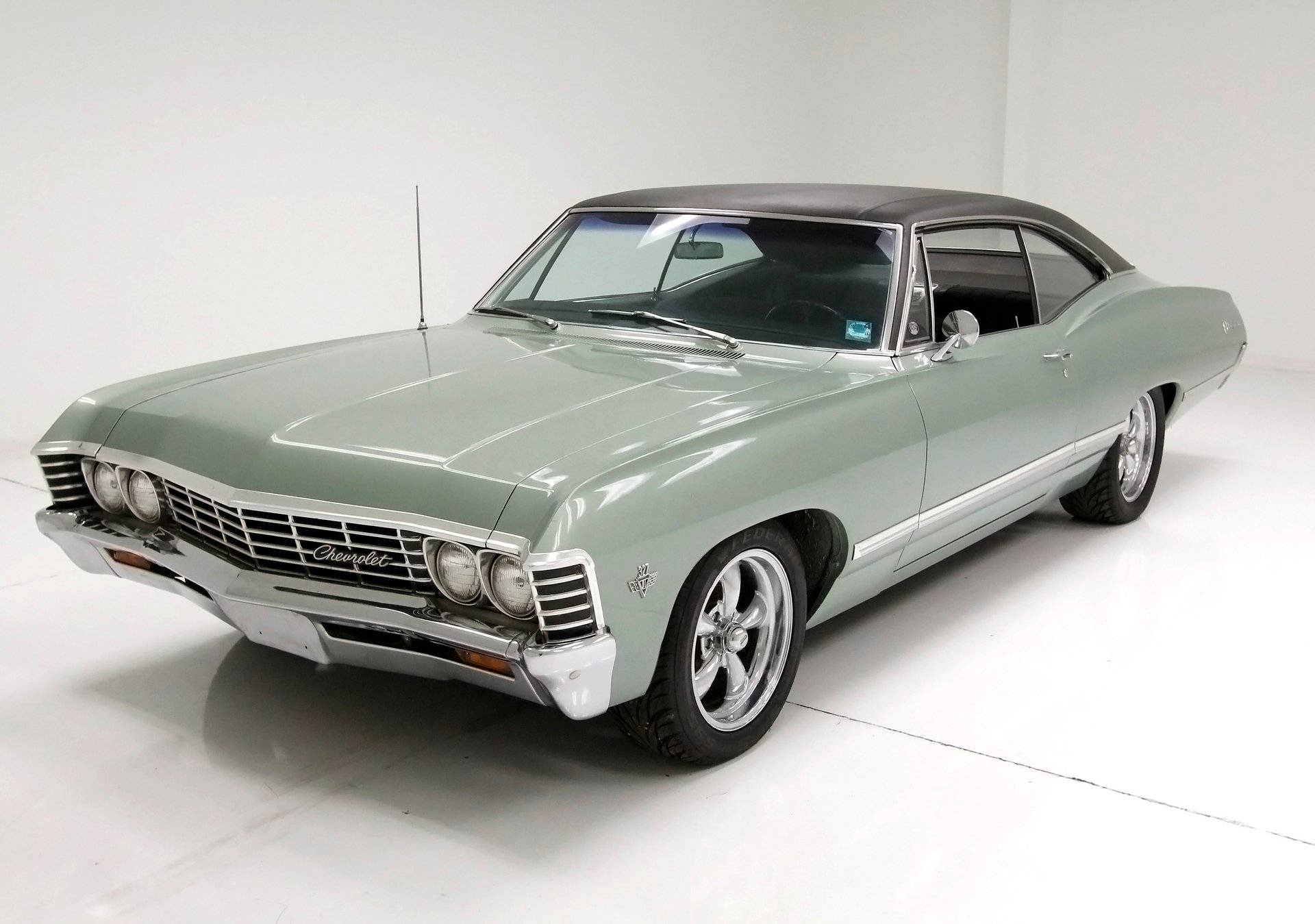 chevrolet impala 1967 桌布 壁紙 — 一輛時尚的薄荷綠經典雪佛蘭，黑色車頂和鍍鉻細節在明亮的攝影棚燈光下閃閃發光。
