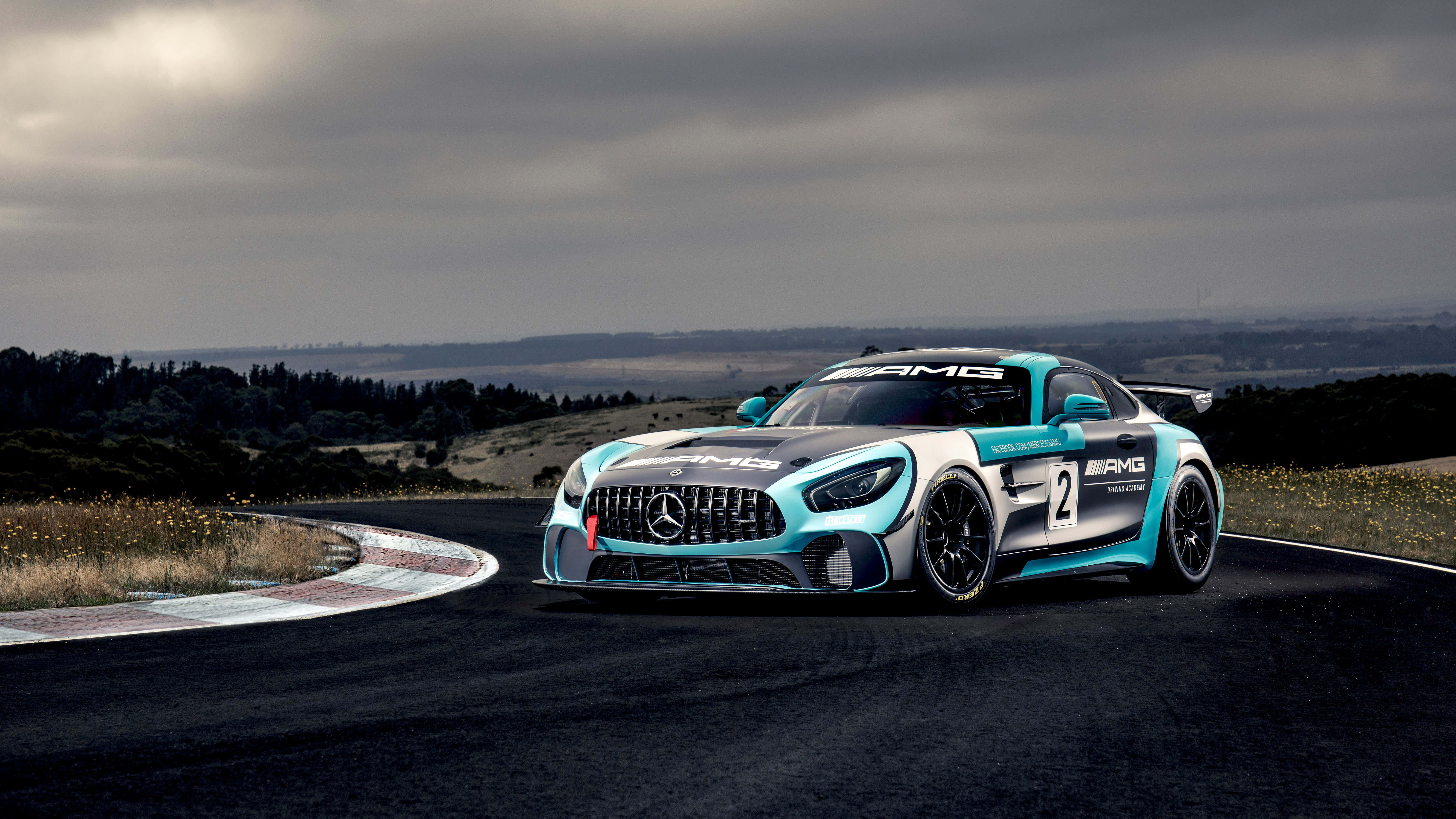 rally 桌布 壁紙 — 一輛時尚的藍白色賓士AMG GT3賽車，編號2，在多雲的天空下沿著蜿蜒的瀝青賽道飛馳。