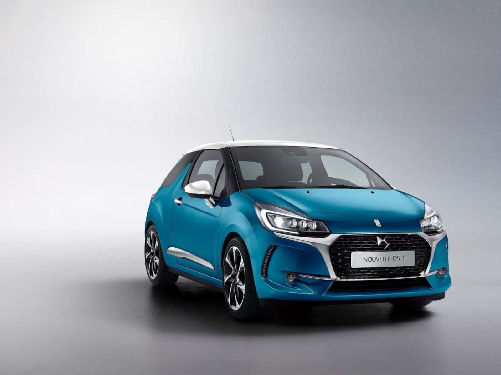 Ds Automobiles 桌布 壁紙 — 一輛時尚的藍綠色DS 3掀背車，白色車頂和銀色飾邊，在極簡灰色工作室背景前擺拍。