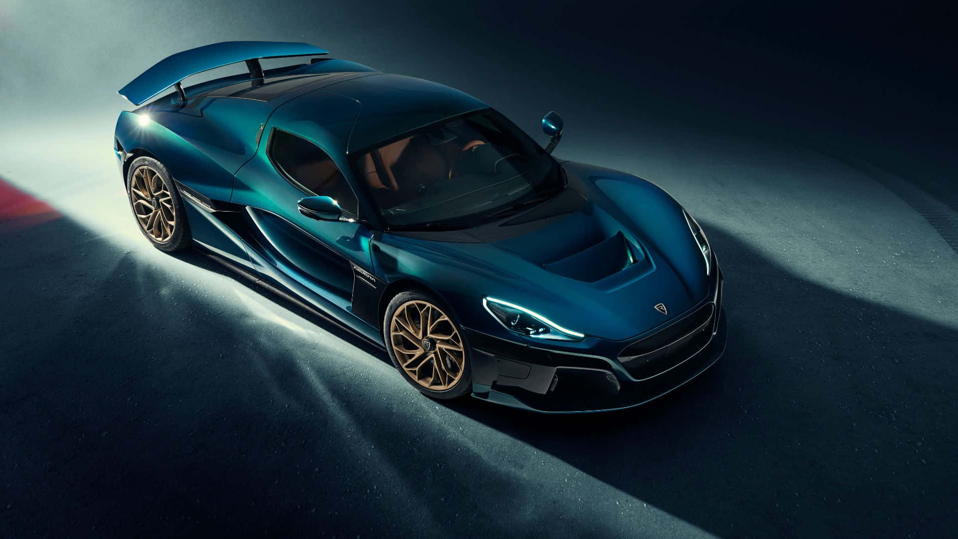 Rimac 桌布 壁紙 — 一輛時尚的藍綠色超級跑車配金色輪圈，在黑暗的攝影棚地板上，於戲劇性的聚光燈下閃耀。