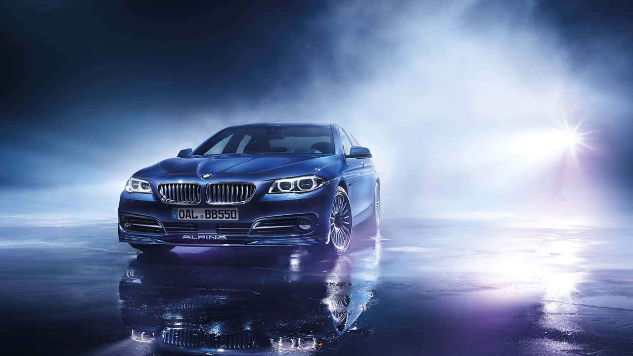 720p Bmw 桌布 壁紙 — 一輛時尚的藍色Alpina BMW轎車在戲劇性的聚光燈下，在潮濕的反光表面和霧氣瀰漫的氛圍中閃閃發光。